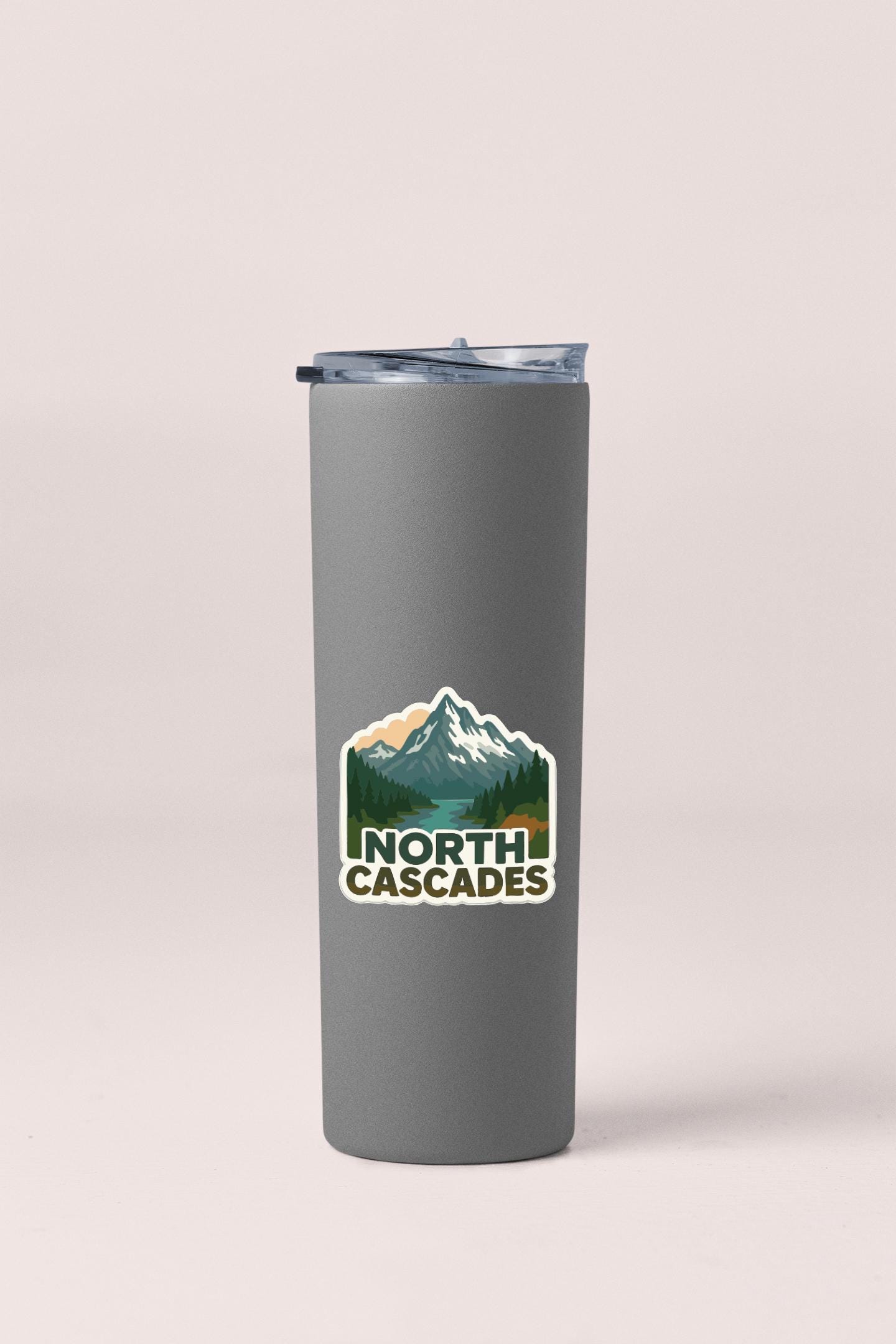 A gray insulated tumbler with a mountain landscape sticker on it.