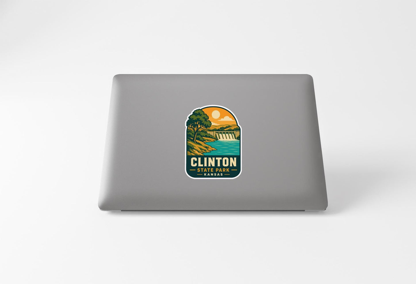 A sticker on the back of a laptop, depicting a scenic landscape with a lake and mountains.