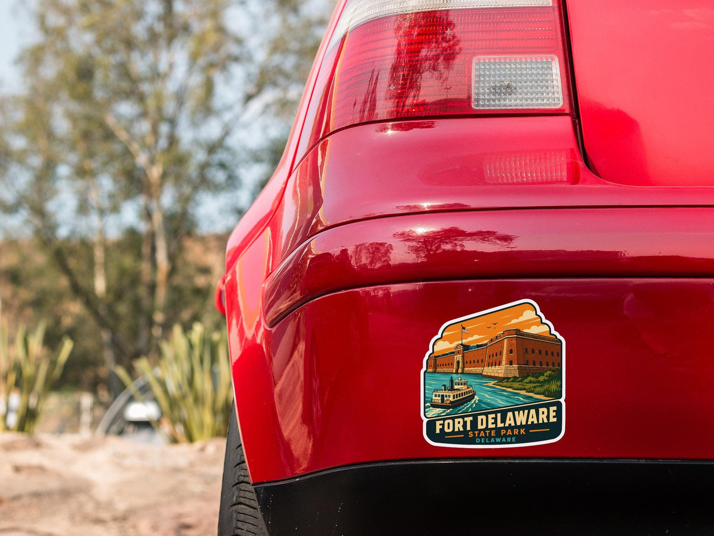 the rear end of a red car with a sticker on the trunk that says "Fort Delaware, Delaware".