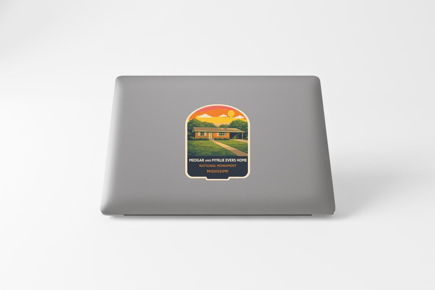 a sticker with a house and a sunset on a laptop.