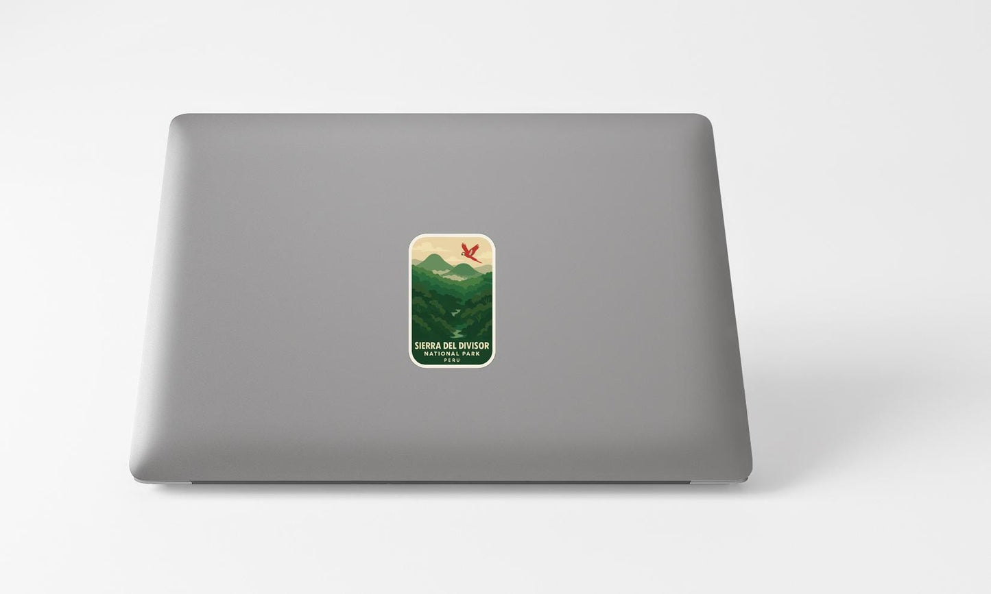 A sticker with a mountain landscape and a bird is placed on the back of a laptop computer.