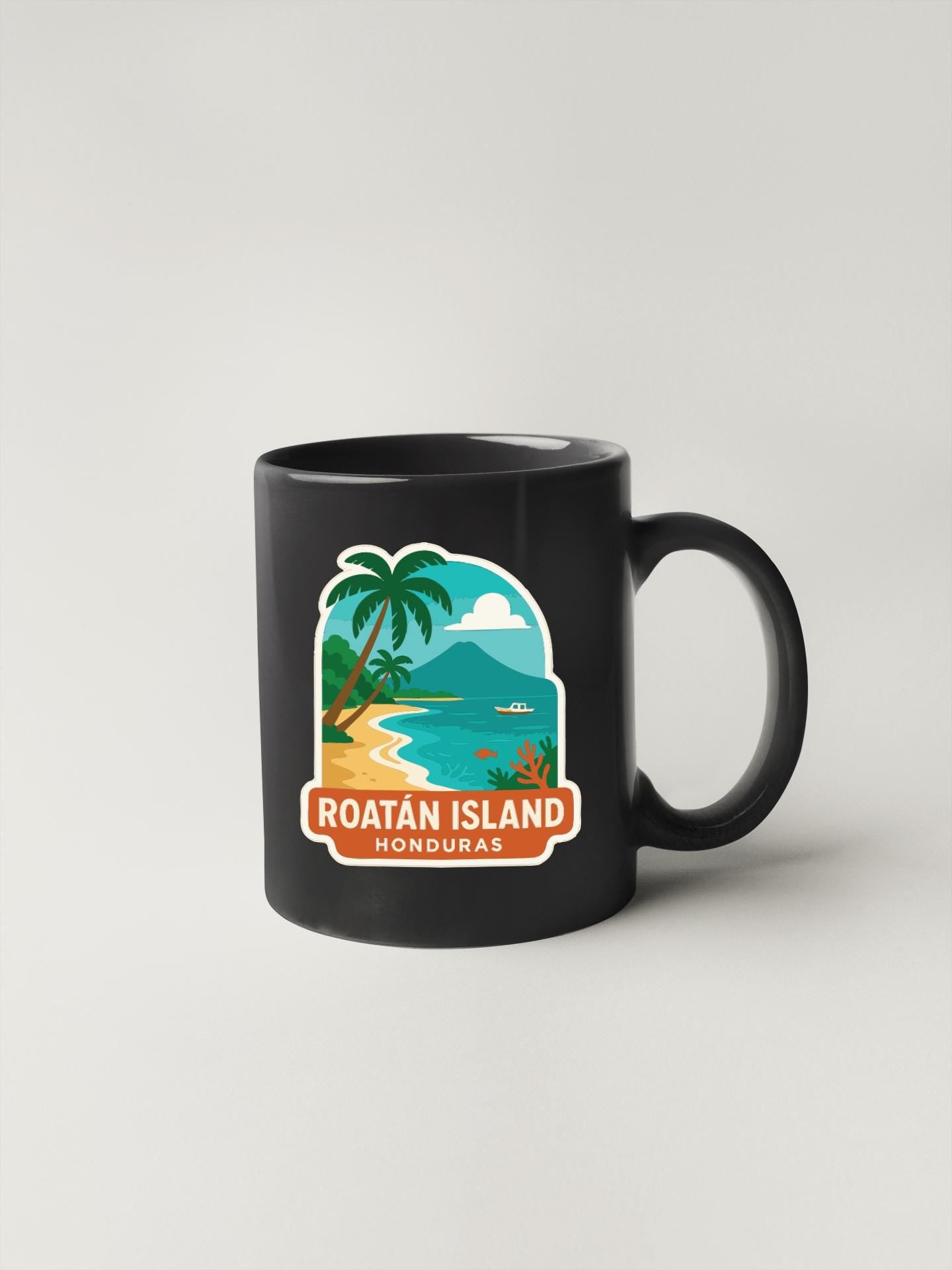 A black coffee mug with a tropical island and palm tree sticker on it, depicting Roatan Island, Honduras.