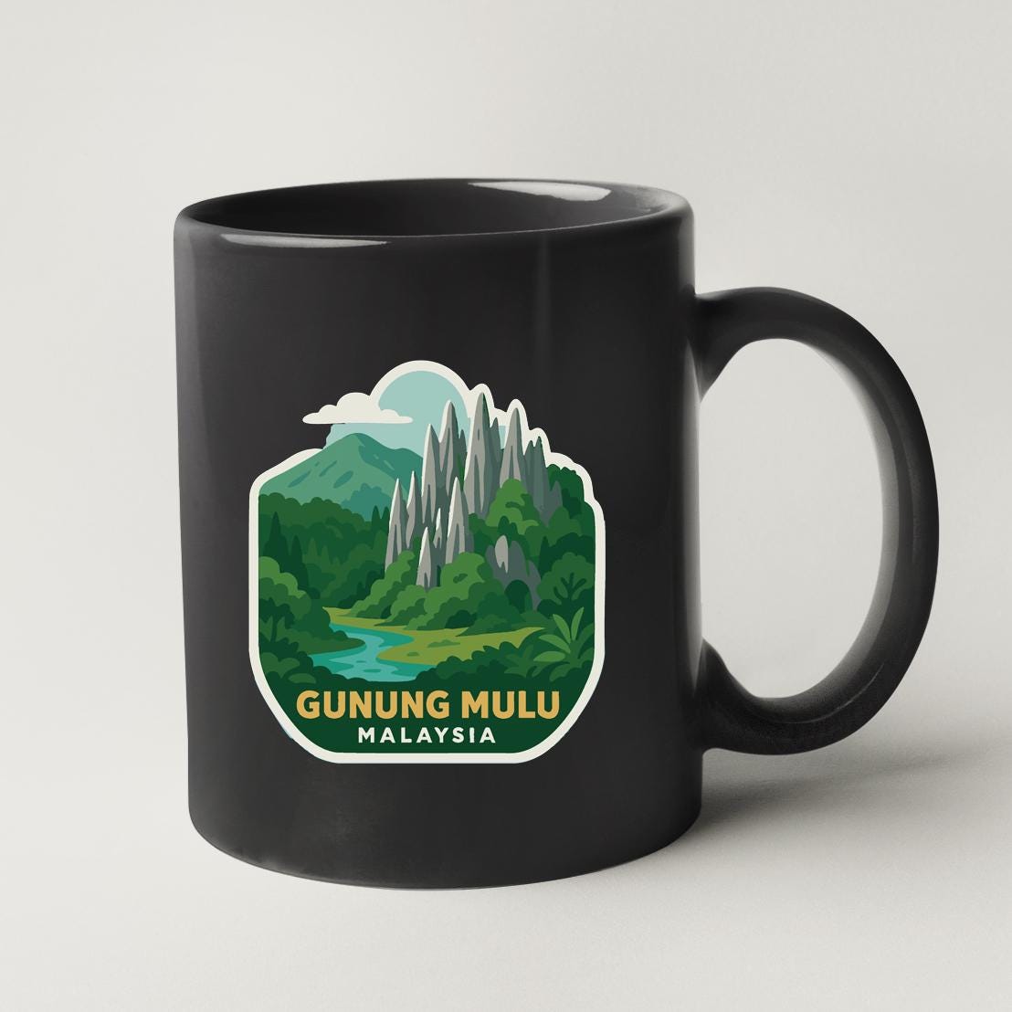A black coffee mug with a graphic design depicting a mountainous landscape with a river, surrounded by lush vegetation.