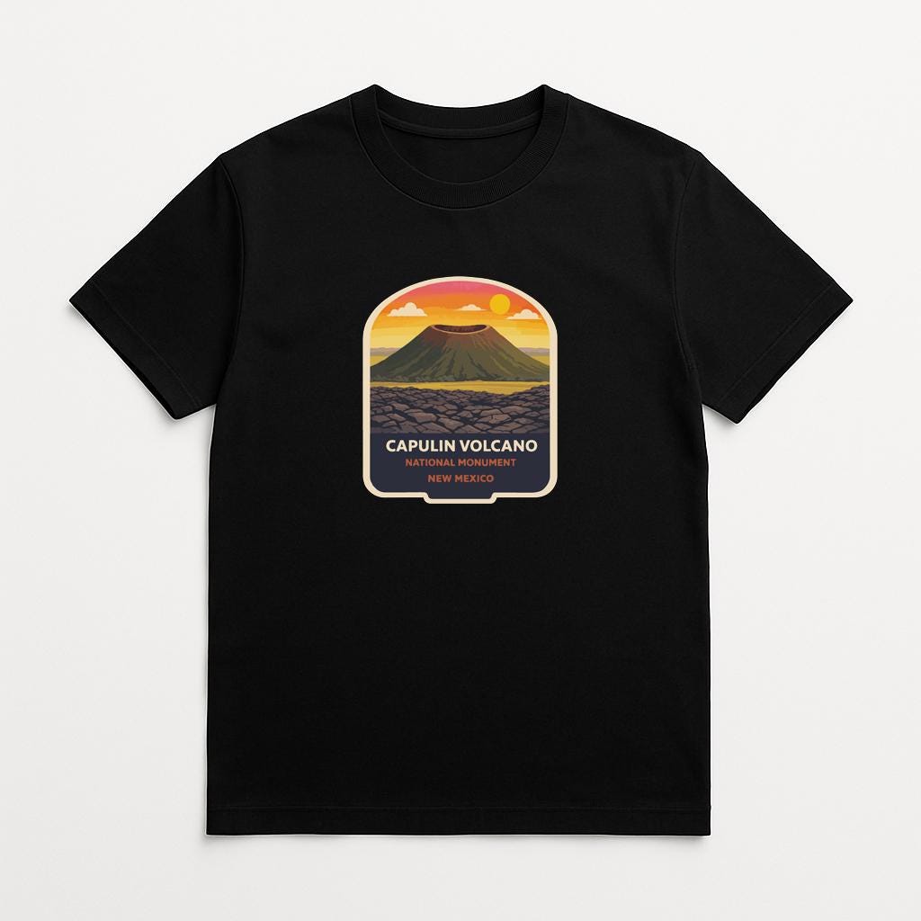 A black t-shirt with a graphic design depicting a volcano and the text "CAPULIN VOLCANO NEW MEXICO" printed on it.