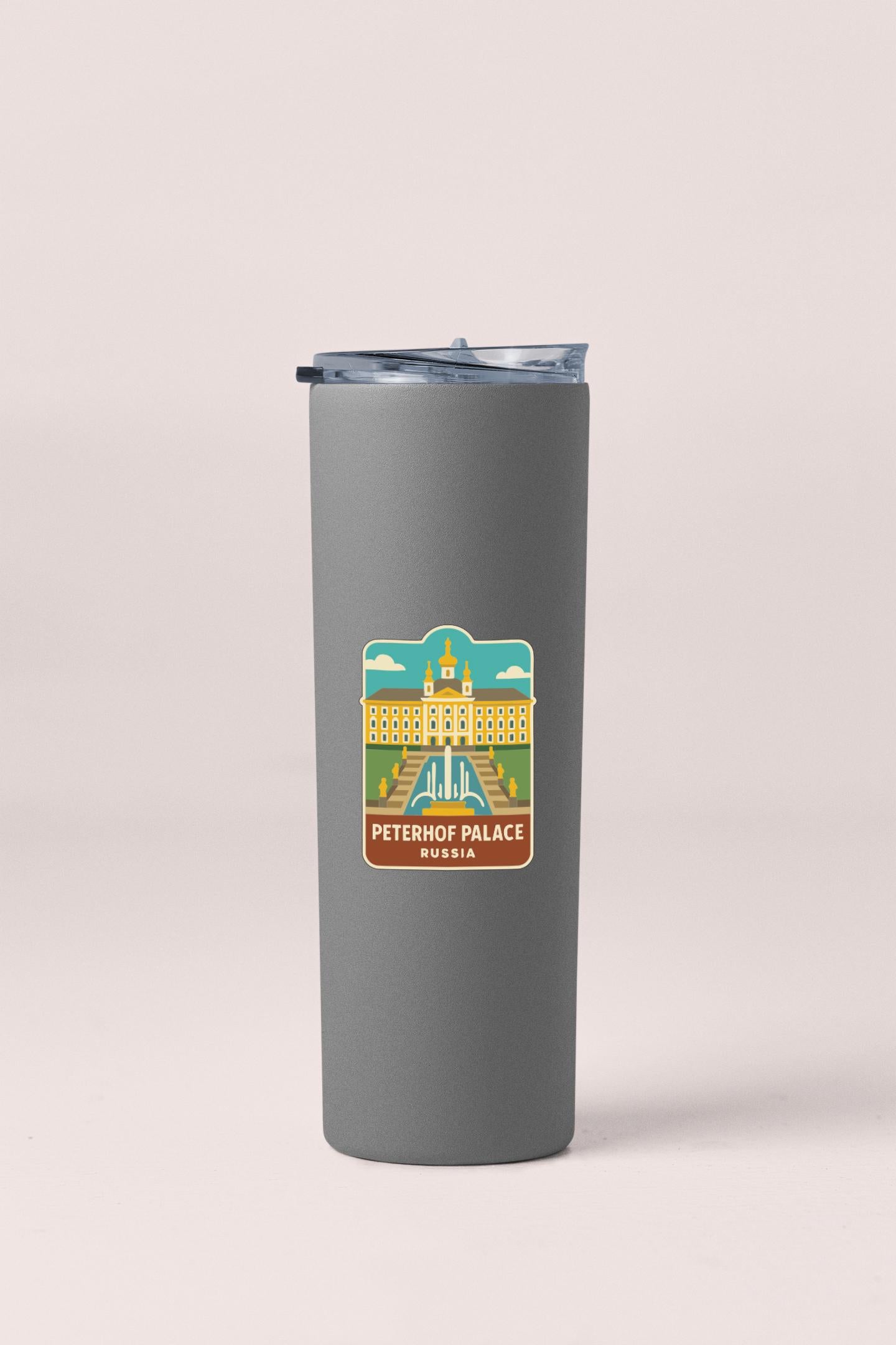 A gray insulated tumbler with a sticker depicting the Peterhof Palace in Russia.