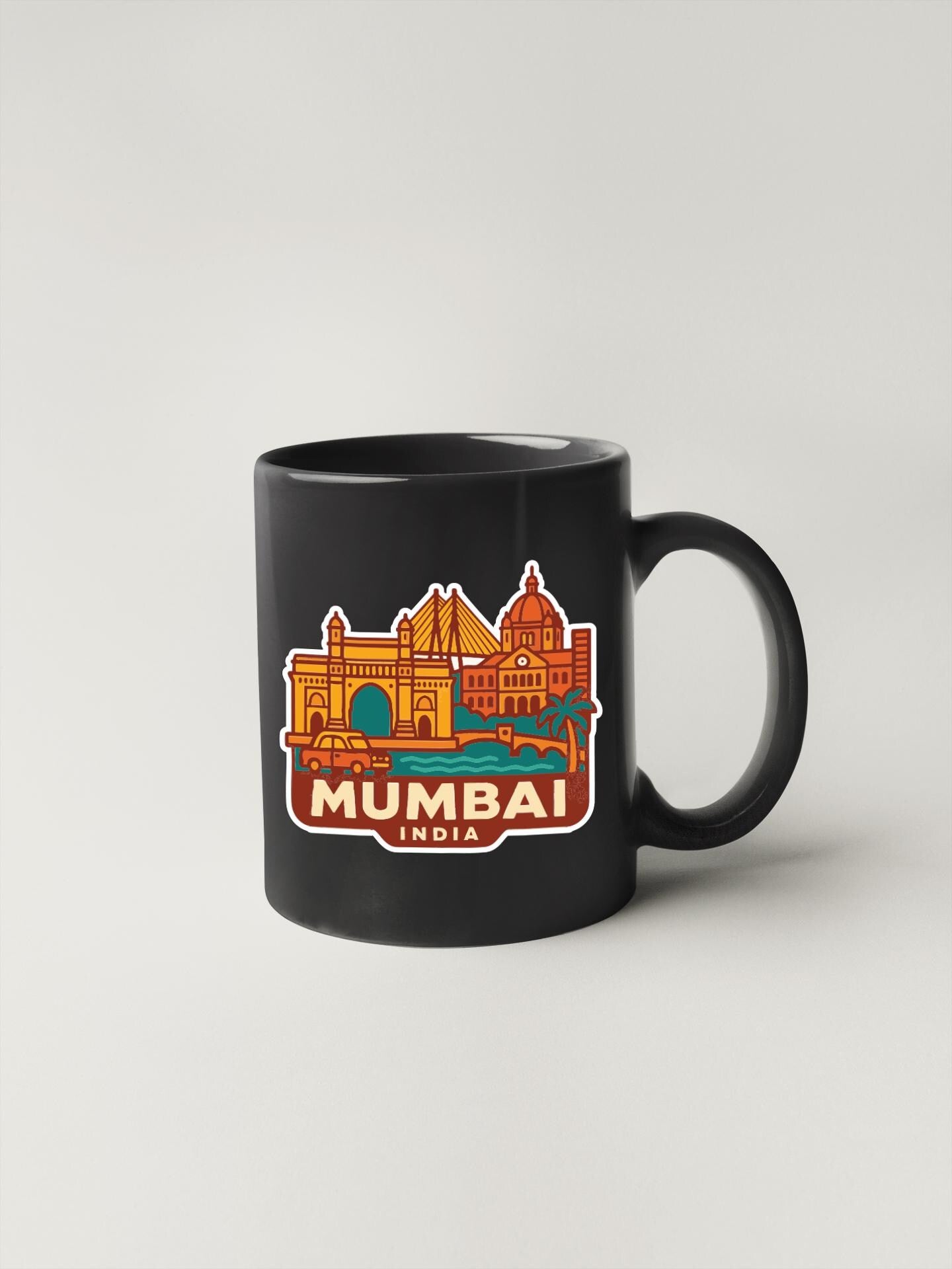 A black coffee mug with a colorful illustration of the Mumbai skyline and text that says "MUMBAI INDIA".