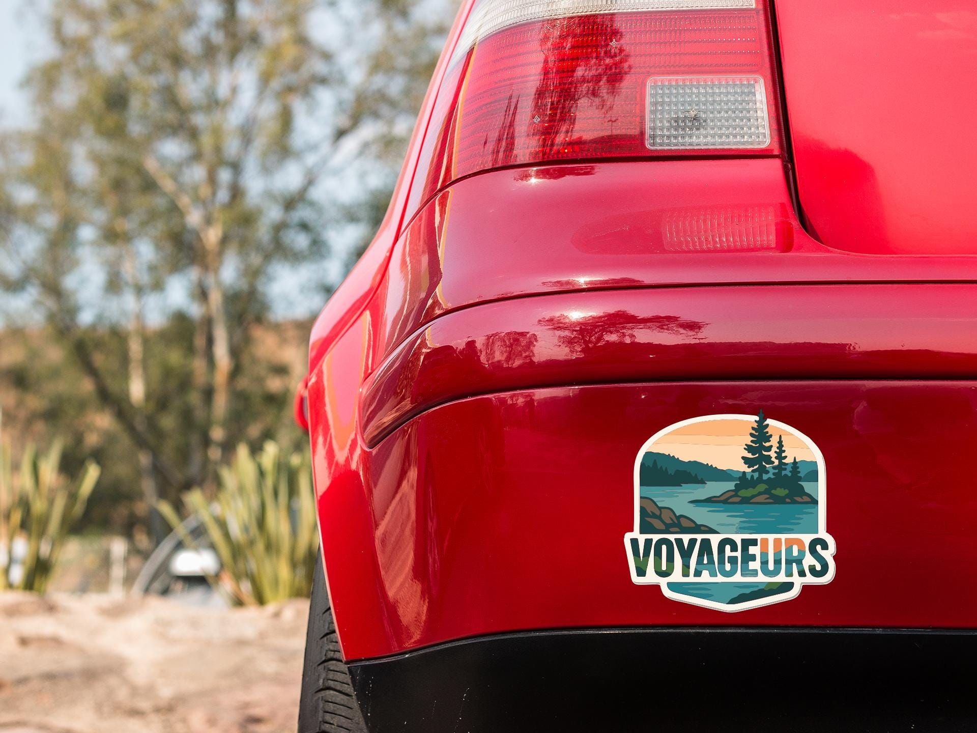 the rear end of a red car with a sticker on the back window that says "VOYAGEURS".