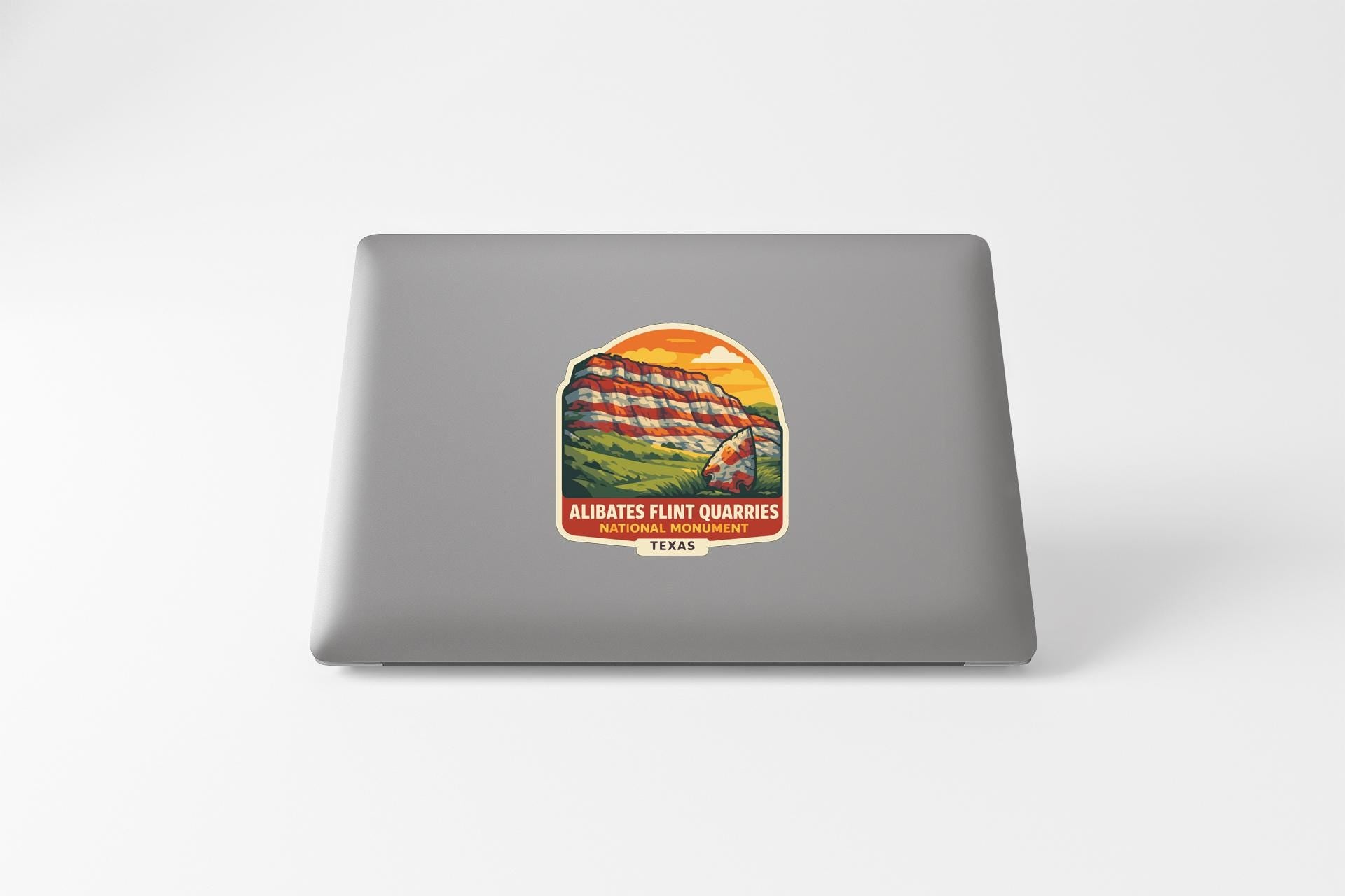 a sticker on the back of a laptop that depicts a scenic landscape with a mountain and a river.