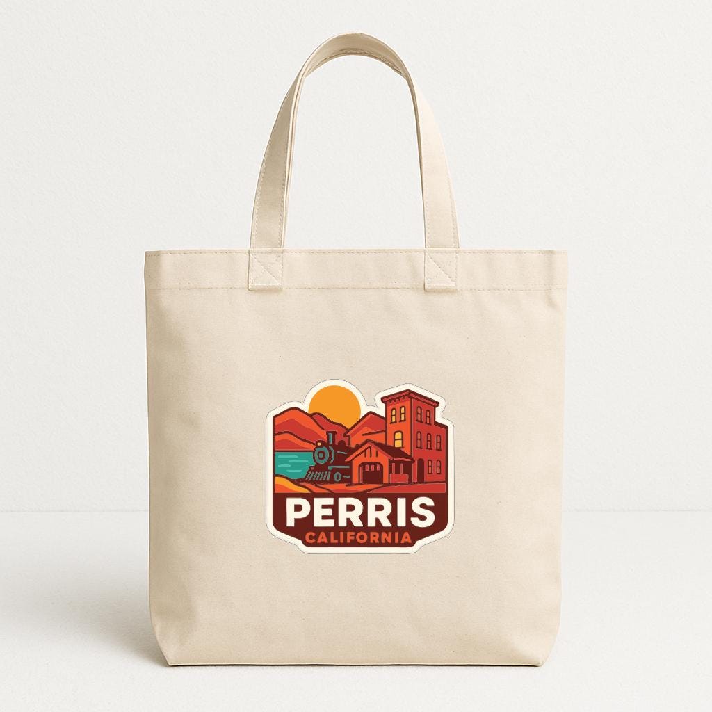 A beige tote bag with a graphic design featuring a train, buildings, and a sunset.