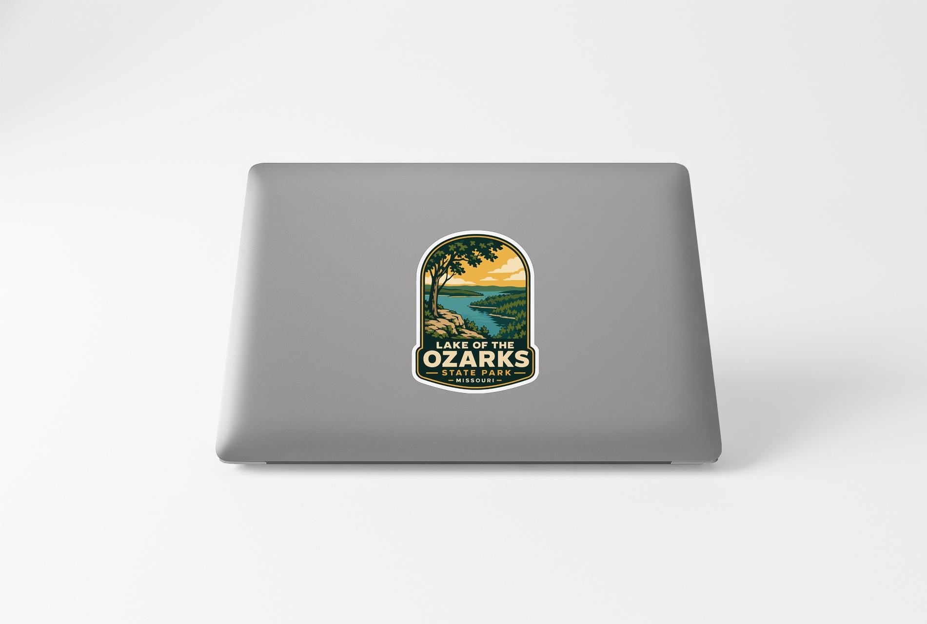 A sticker on the back of a laptop, depicting a scenic landscape with a lake and mountains.