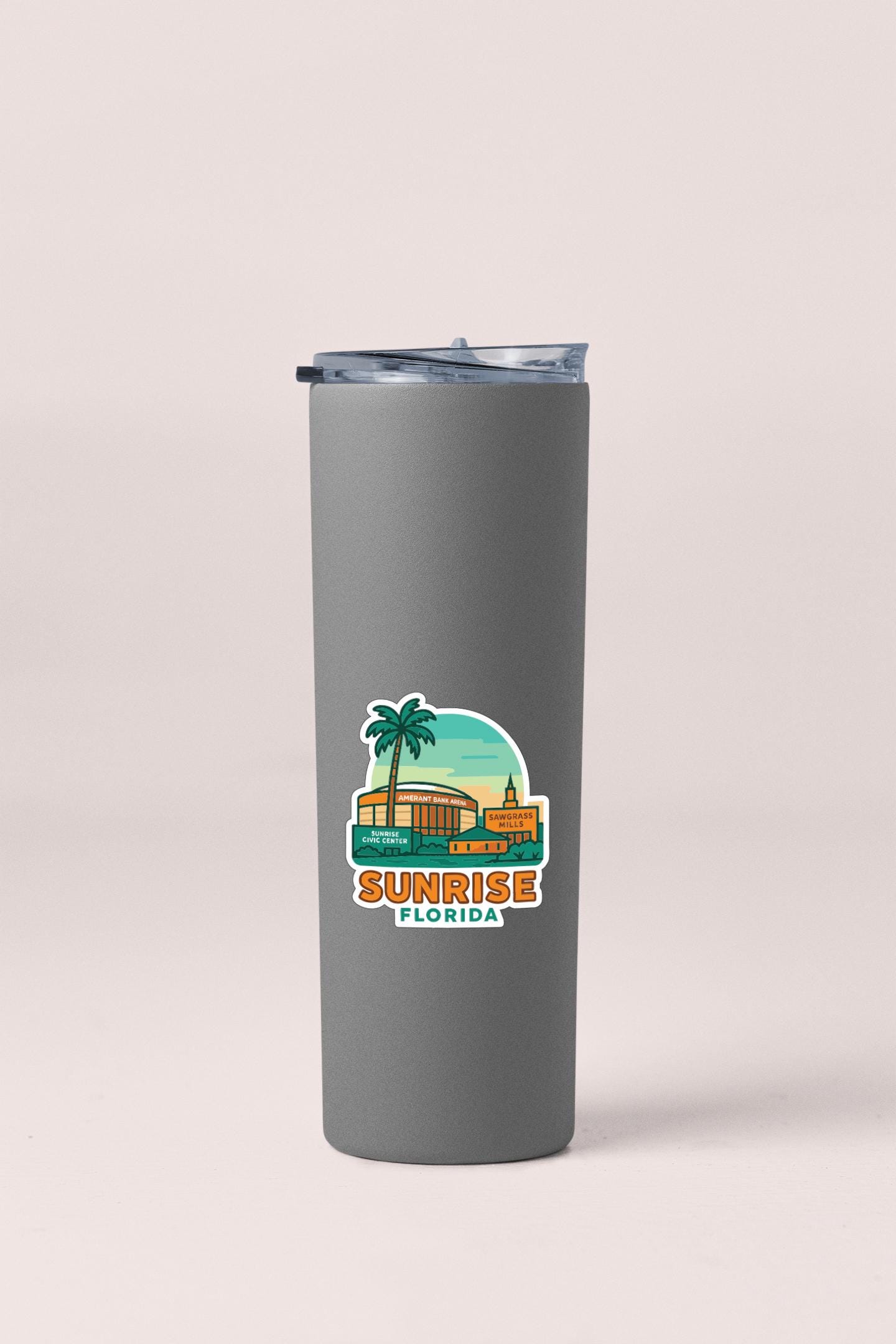 A gray insulated tumbler with a sticker depicting a tropical scene and the text "Sunrise Florida".