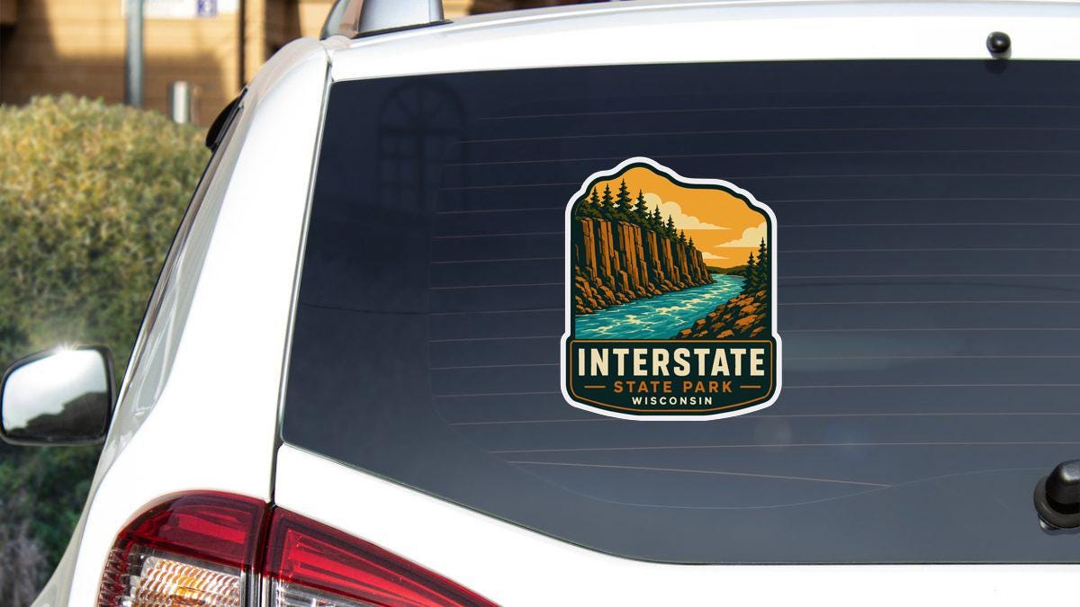 A sticker on the rear window of a vehicle, depicting a scenic landscape with a river and mountains, along with the text "INTERSTATE STATE PARK WISCONSIN".