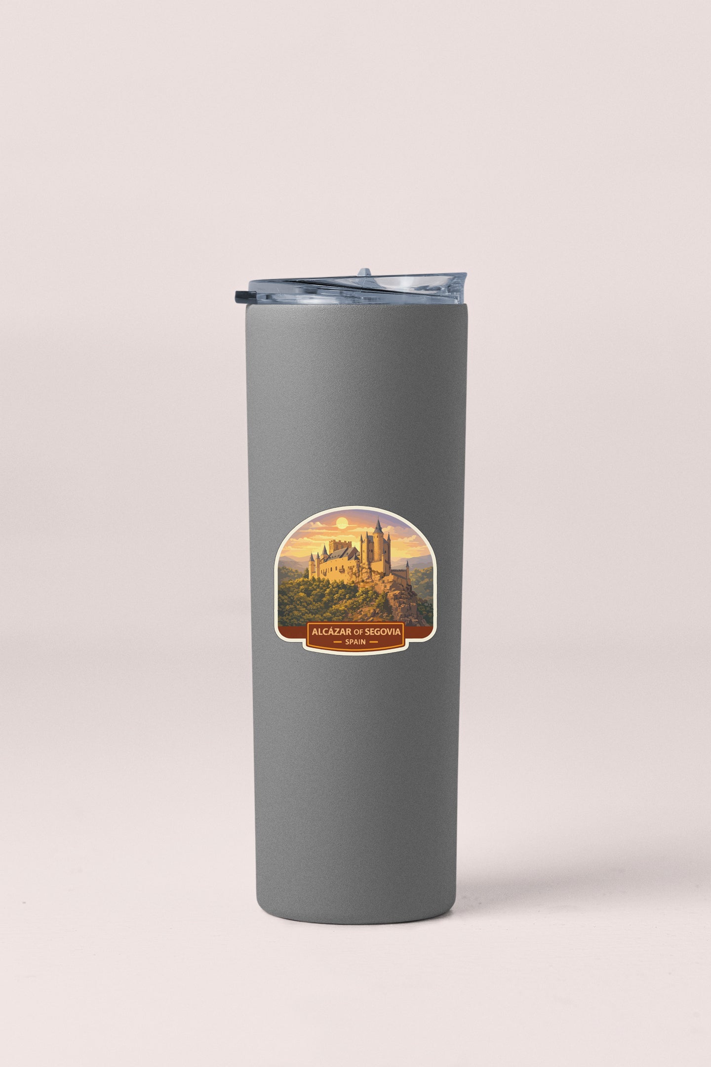 A gray tumbler with a sticker depicting a castle in the background.