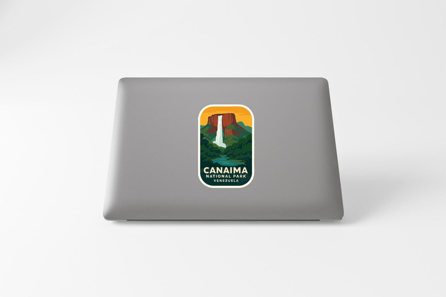 a sticker on the back of a laptop that displays a scenic landscape with a waterfall and mountains.