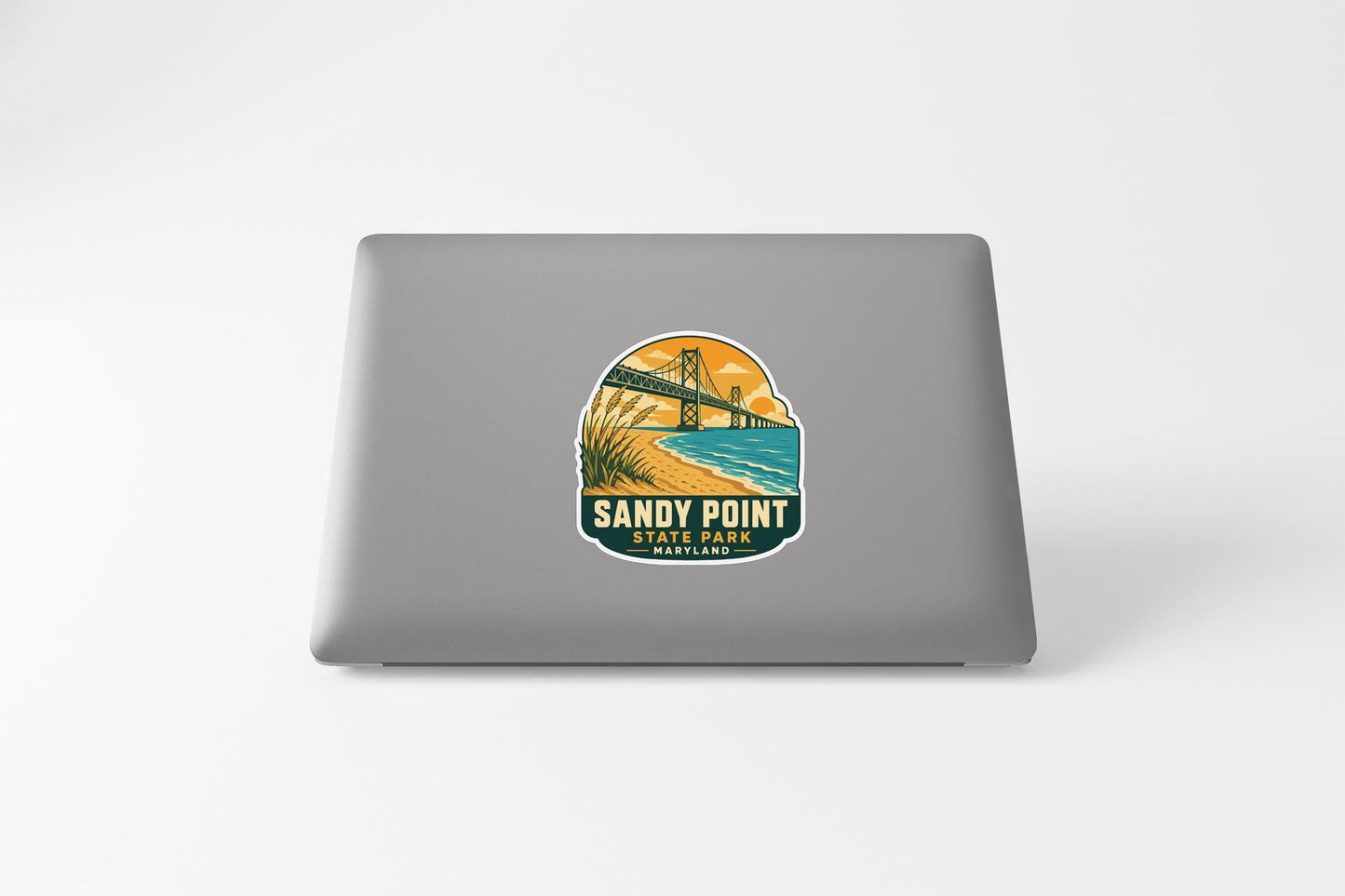 A sticker on the back of a laptop, depicting a scenic landscape with a bridge and a beach.