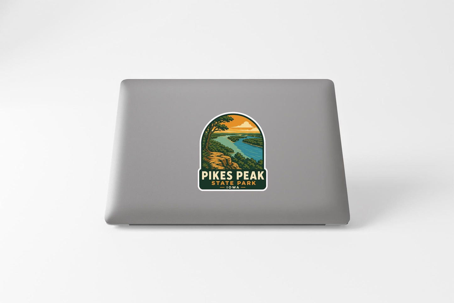A sticker on the back of a laptop, depicting a scenic landscape with a river and mountains.