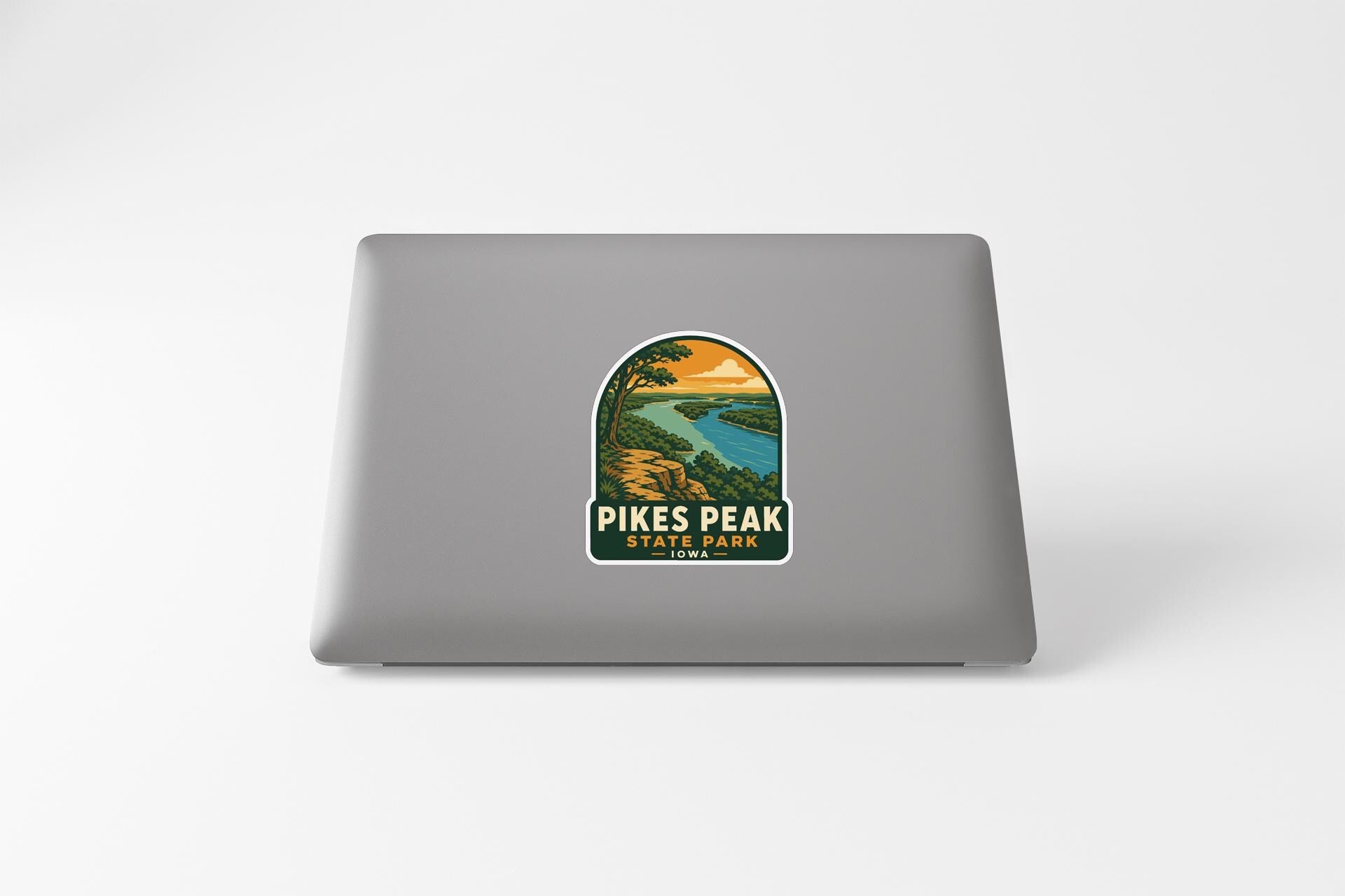 A sticker on the back of a laptop, depicting a scenic landscape with a river and mountains.