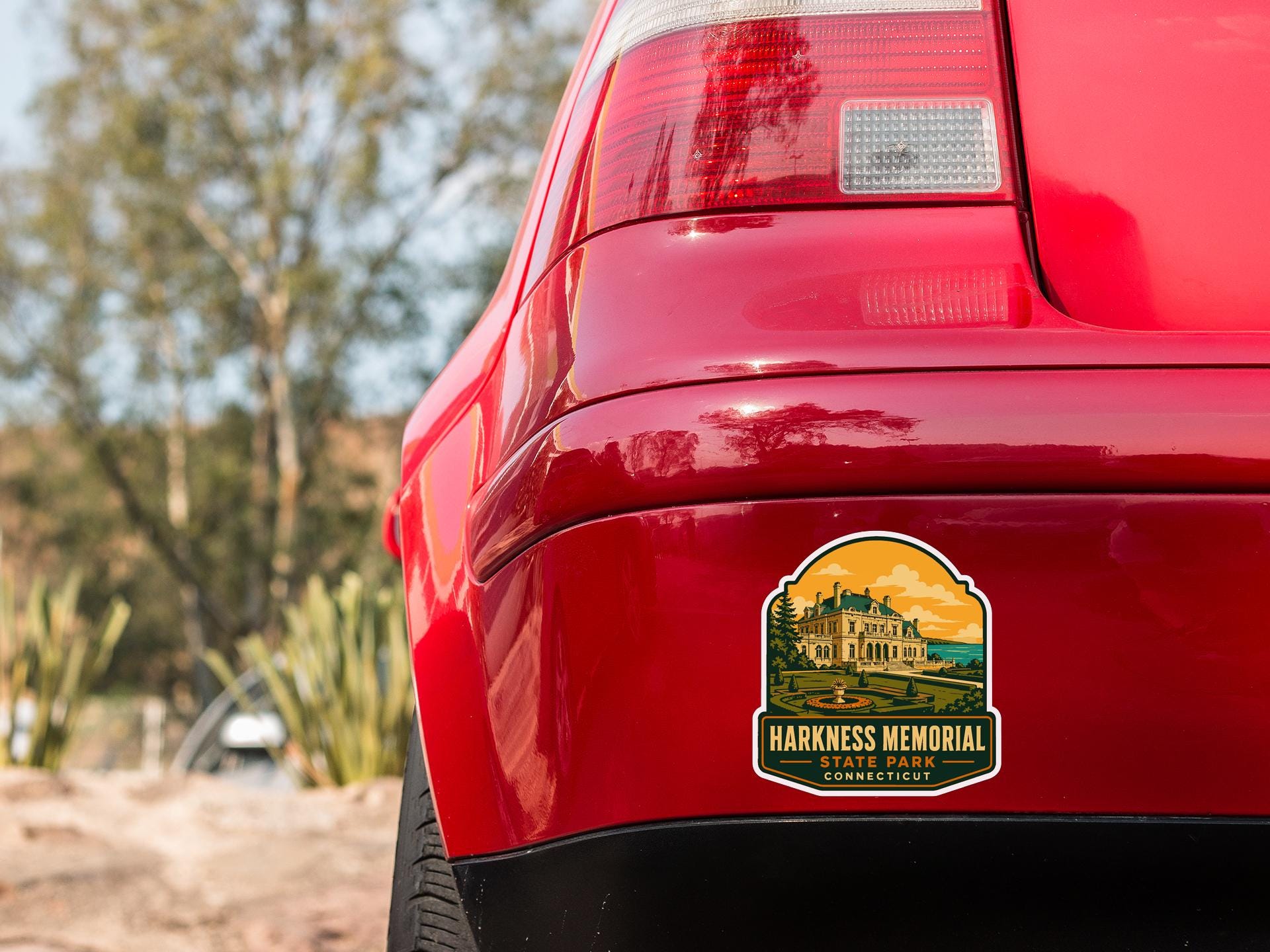 the rear end of a red car with a sticker on the trunk that says "HACKNESS MEMORY STATE PARK CONNECTICUT".