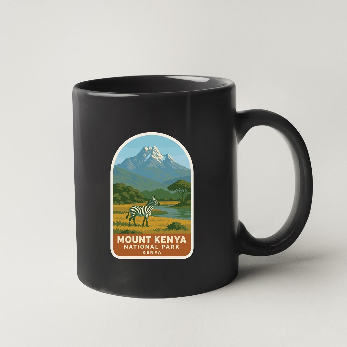 A black coffee mug with a label that features a zebra and a mountain landscape, along with the text "Mount Kenya National Park Kenya".