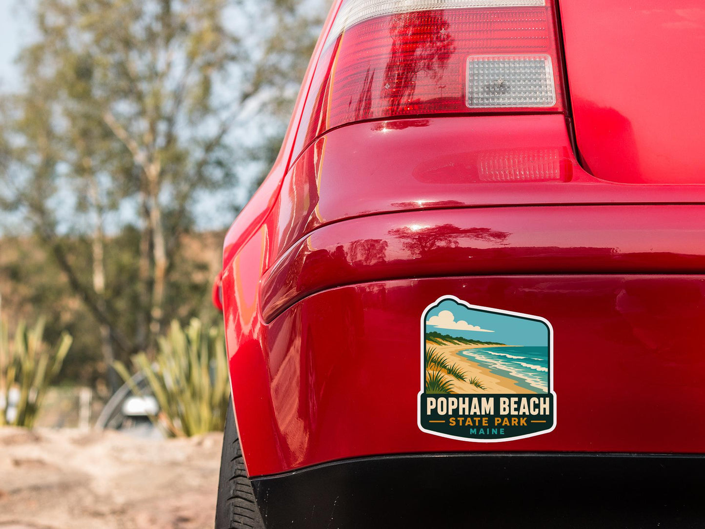 the rear end of a red car with a sticker on the back window that says "POPHAM BEACH STATE PARK MINE".