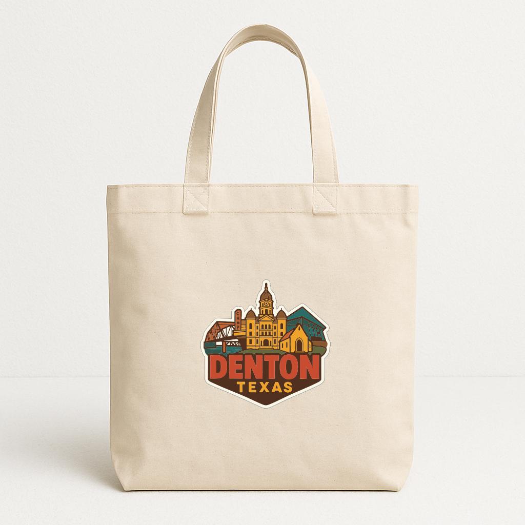 A beige tote bag with a printed design of a city skyline and the text "DENTON TEXAS" on it.