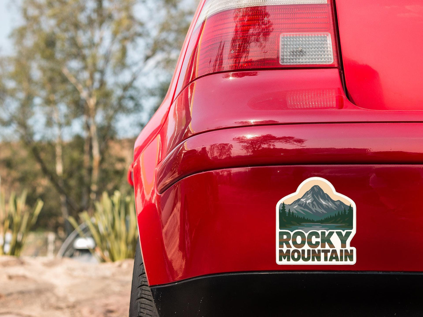the rear end of a red car with a sticker on the back window that says "Rocky Mountain".