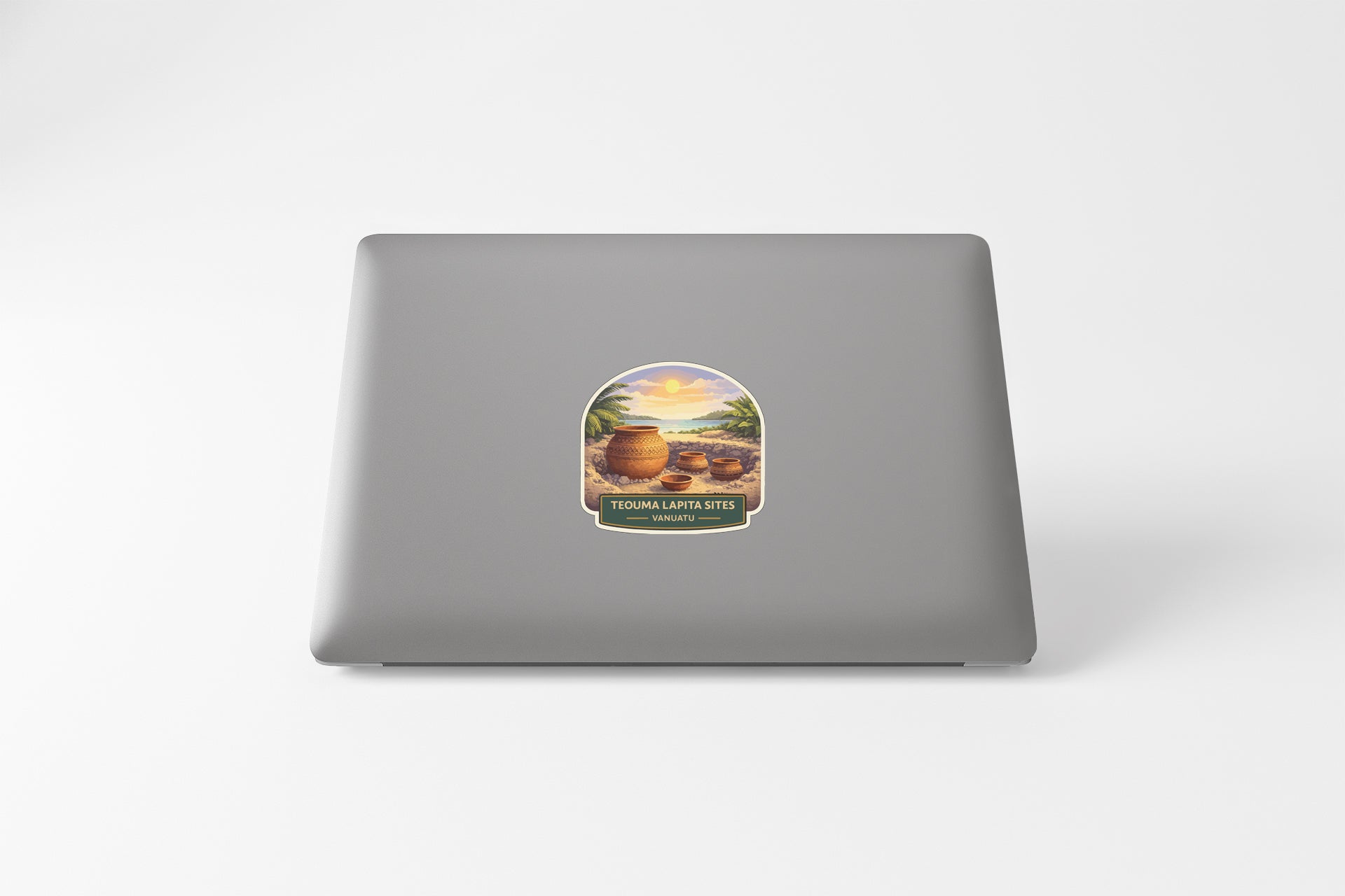 a sticker on the back of a laptop, depicting a tropical scene with palm trees, a sunset, and barrels.
