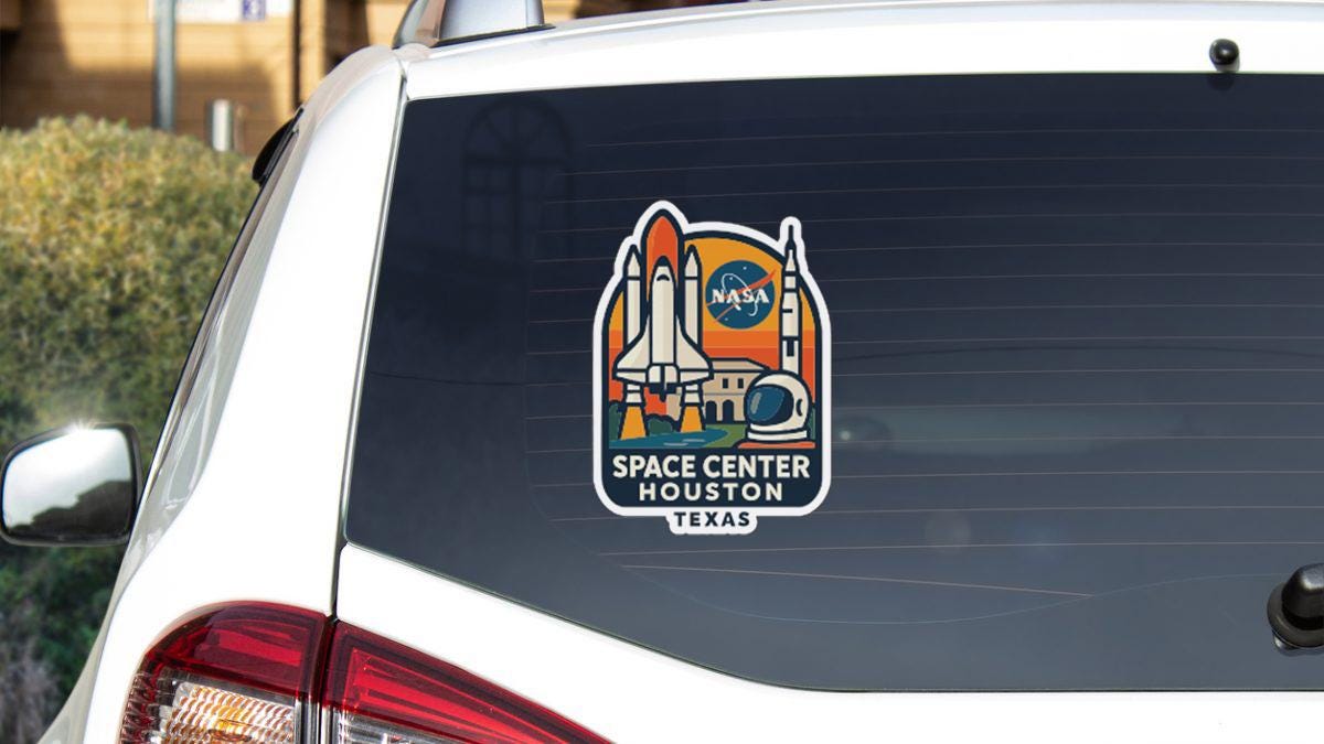 a sticker on the rear window of a vehicle, depicting a space shuttle and the NASA logo, with the text "SPACE CENTER HUSTON TEXAS" below it.