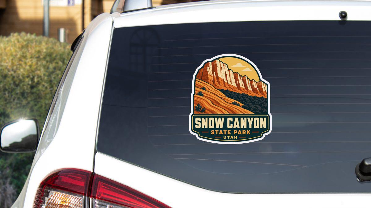 A sticker on the rear window of a white car, depicting a scenic landscape with mountains and a desert.