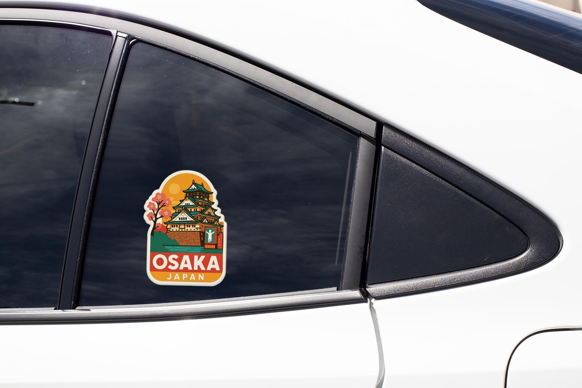 A sticker on the side of a car window, depicting a castle or palace with the text "OSAKA JAPAN" printed on it.