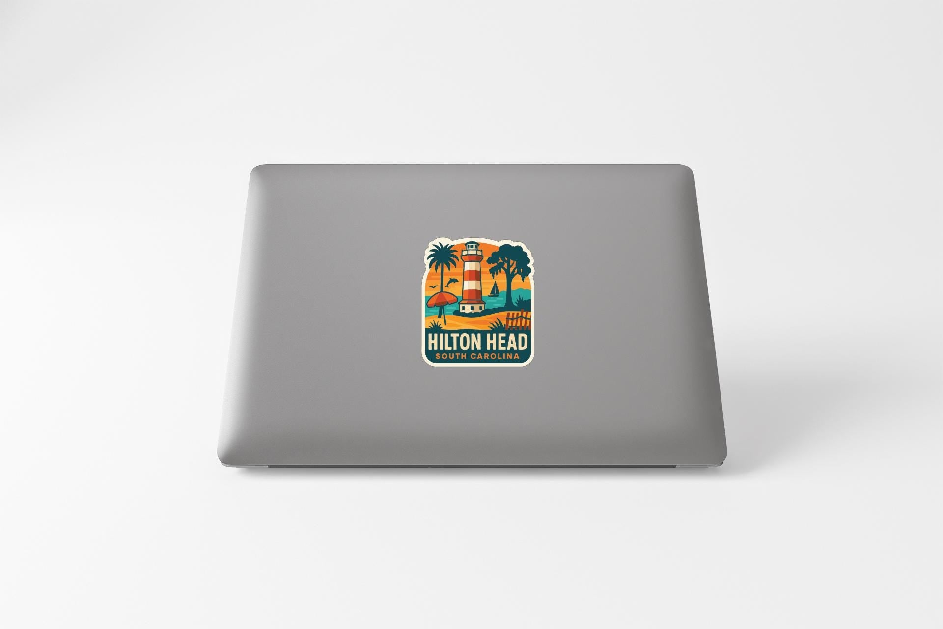 a sticker with a lighthouse and palm trees on a laptop.