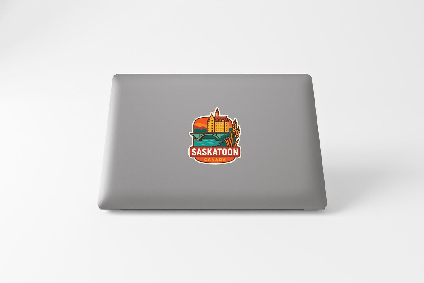 a sticker with a graphic of a building and the text "Saskatoon, Canada" on a laptop.