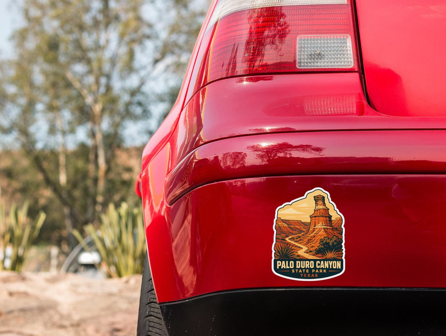 the rear end of a red car with a sticker on the back window that says "Palo Duro Canyon, Texas".