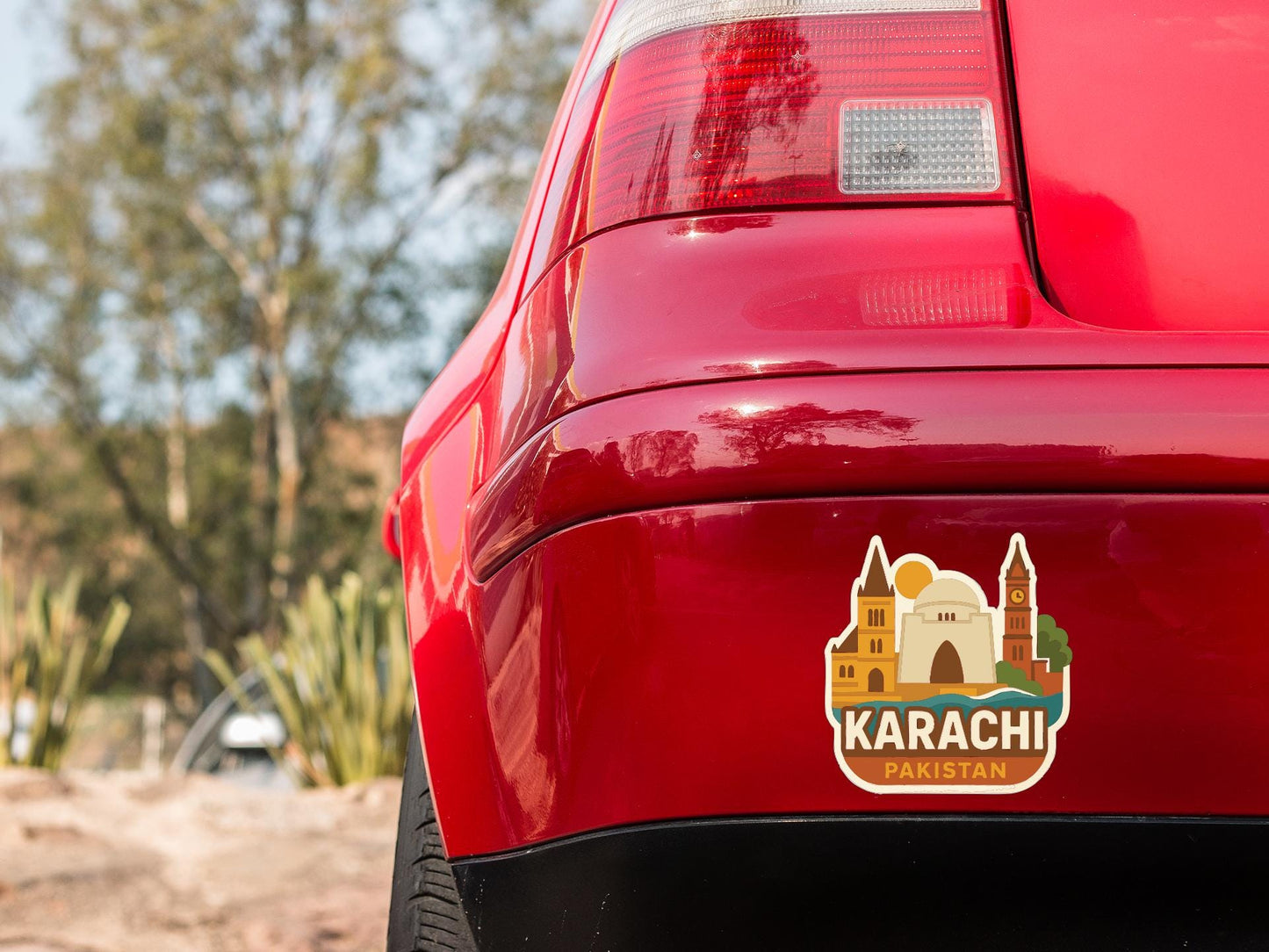 the rear end of a red car with a sticker on the back window that says "KARACHI PAKISTAN".