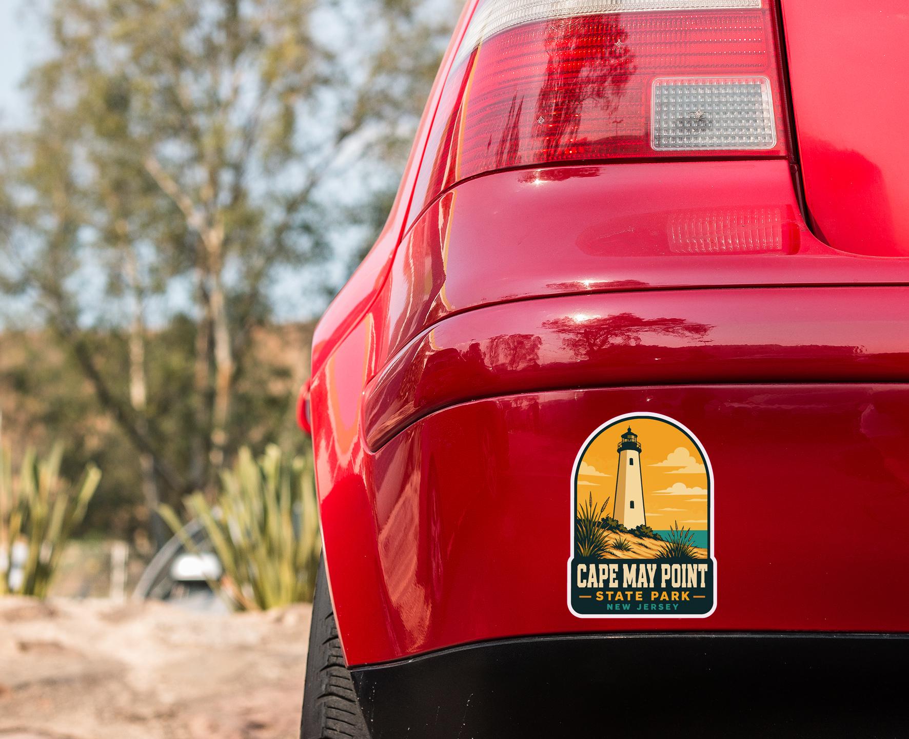 the rear end of a red car with a Cape May Point State Park sticker on the trunk.