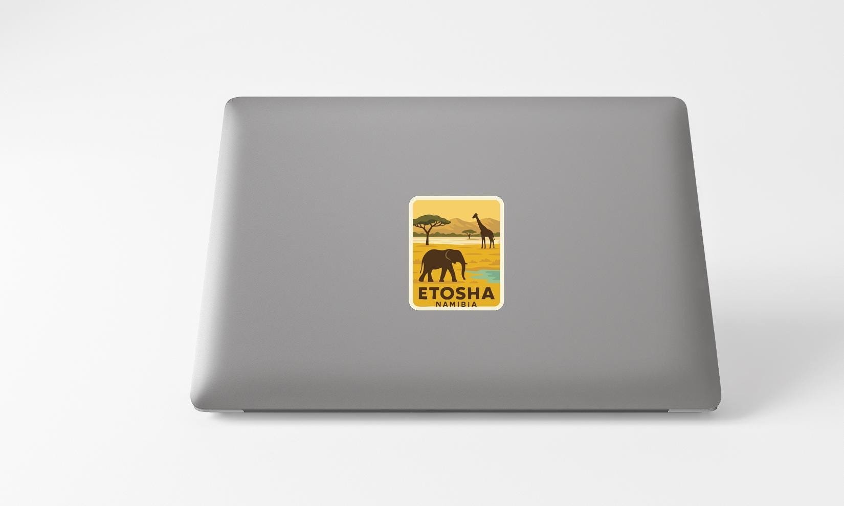 A sticker on the back of a laptop, depicting an elephant and giraffe in a savanna landscape.