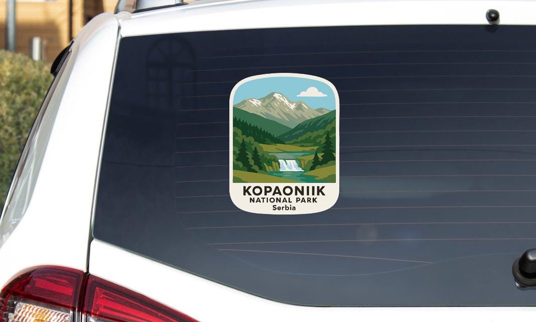A sticker on the rear window of a car, depicting a scenic mountain landscape with a waterfall.