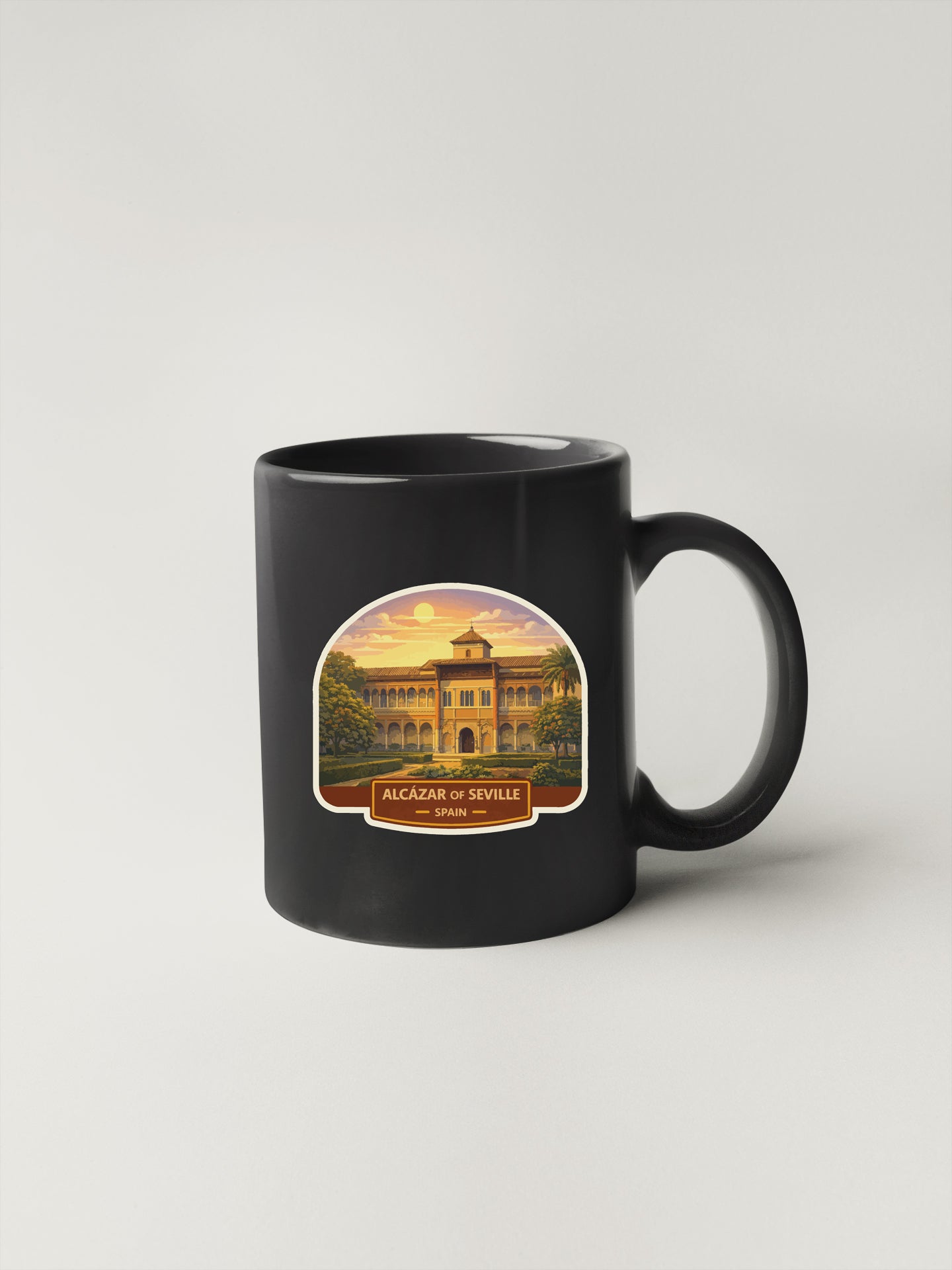 A black coffee mug with a sticker depicting the Alcazar of Seville, Spain.