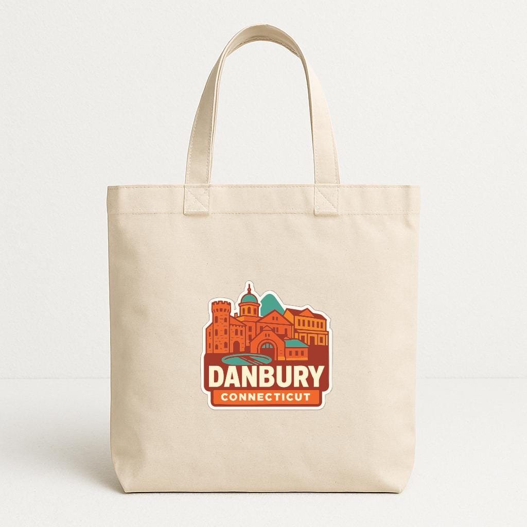 A beige tote bag with a printed design of a city skyline and the text "DANBURY CONNECTICUT" printed on it.