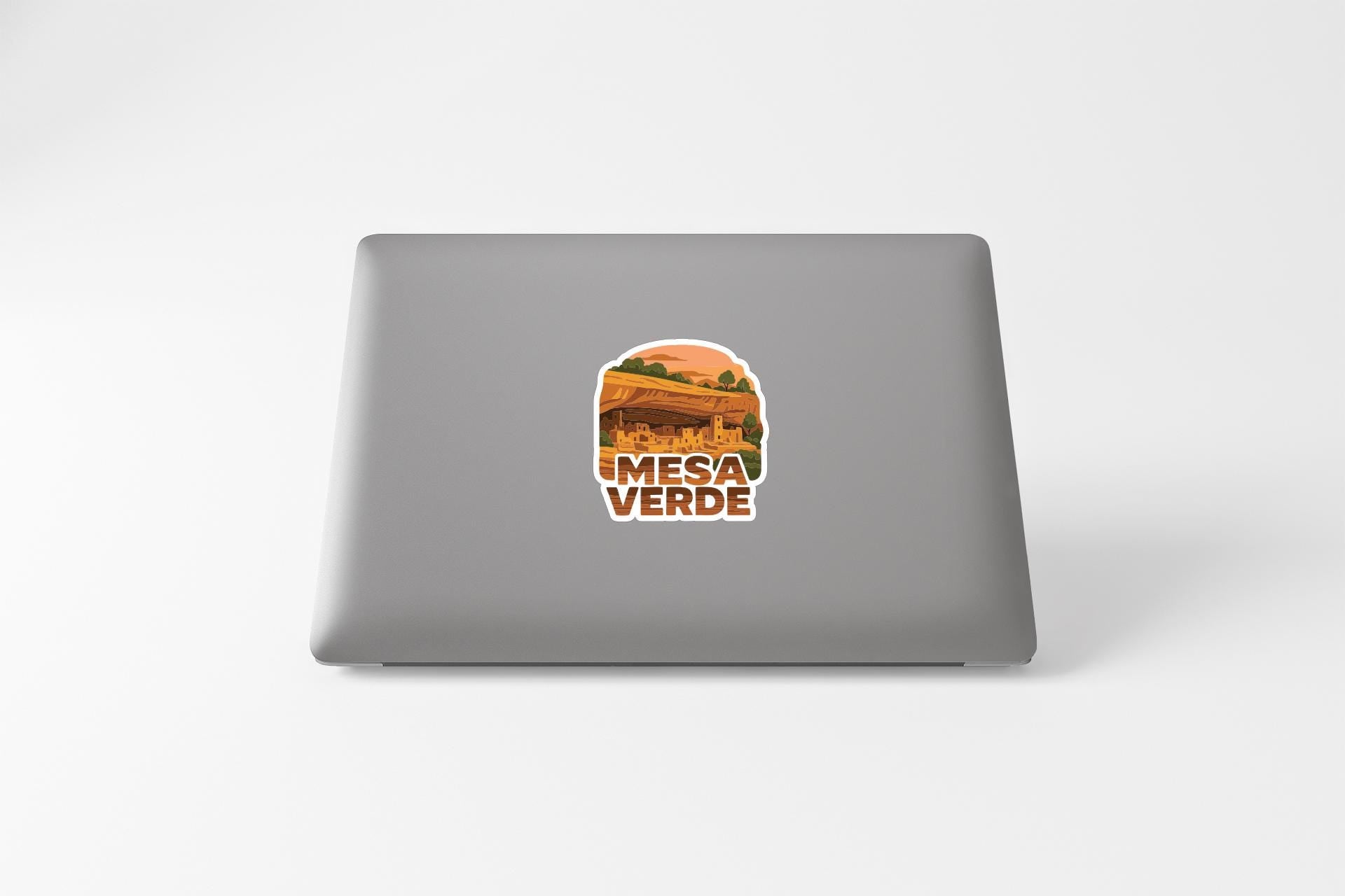 a sticker with a graphic of a desert landscape and the text "MESA VERDE" on the back of a laptop.
