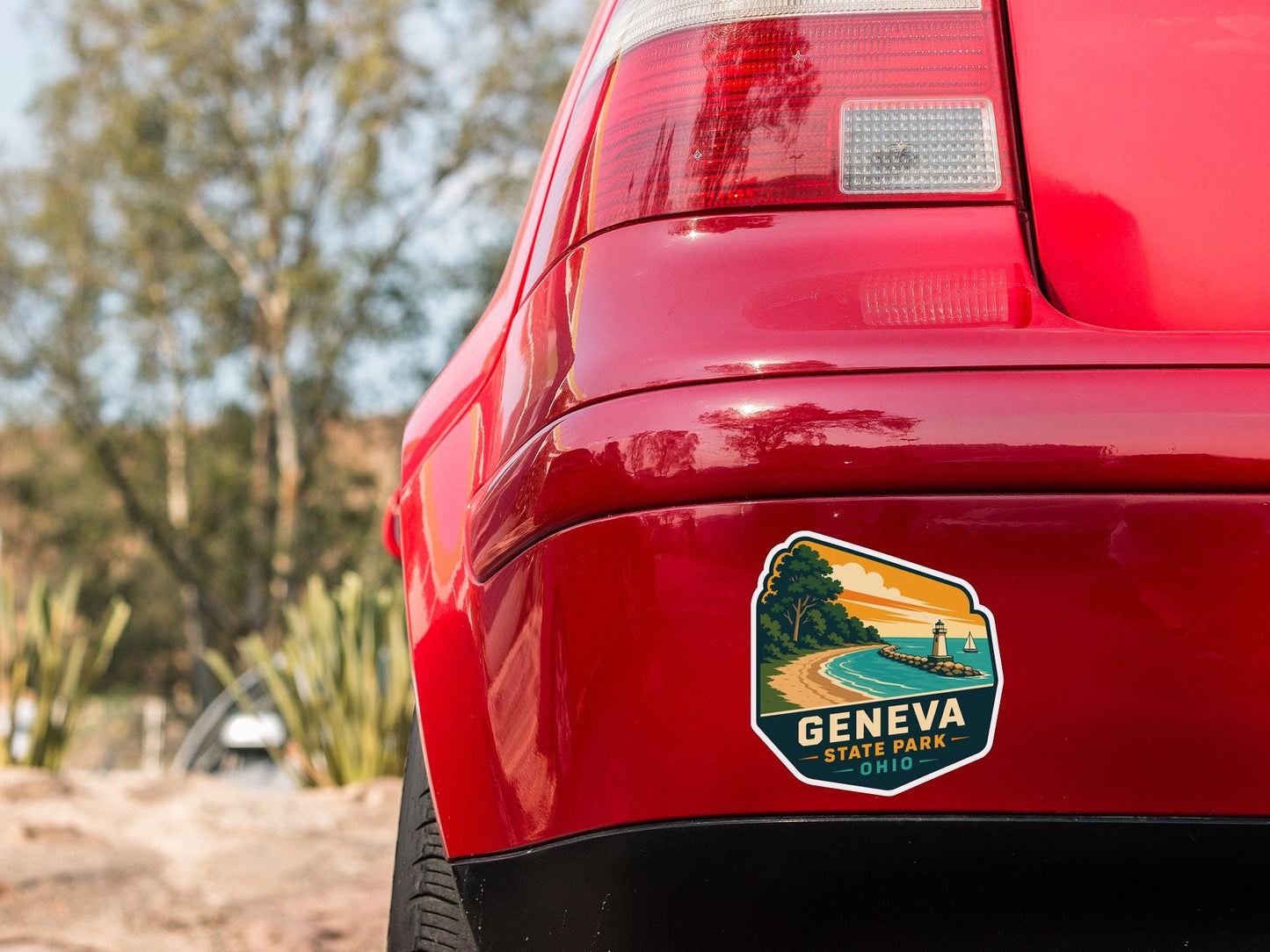 the rear end of a red car with a sticker on the trunk that says "GENCIA STATE PARK".