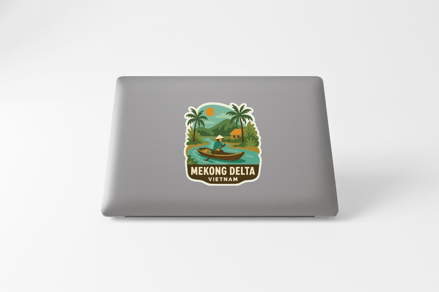 A sticker on the back of a laptop that features a tropical scene with palm trees, a boat, and a person, along with the text "Mekong Delta Vietnam".