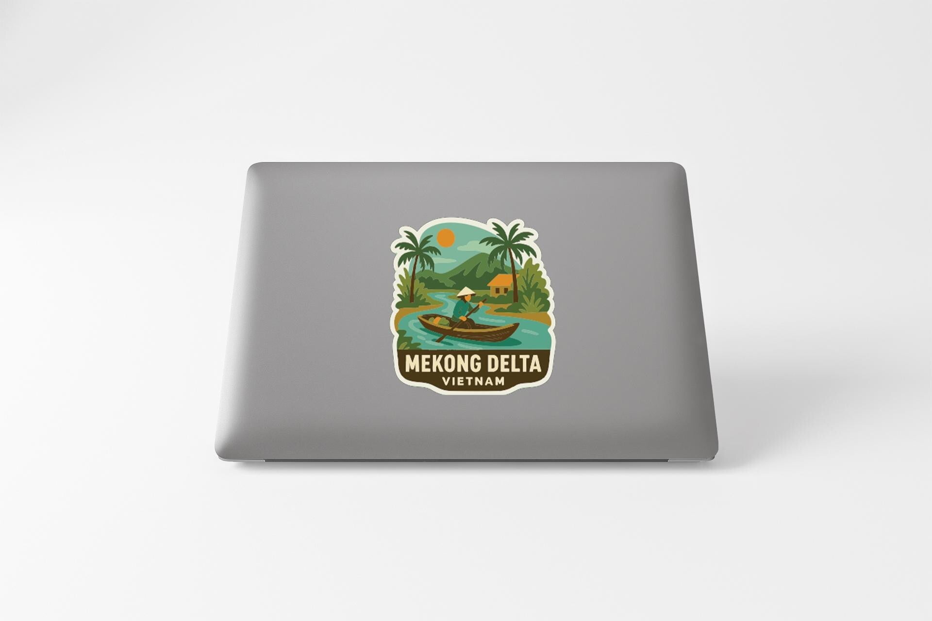 A sticker on the back of a laptop that features a tropical scene with palm trees, a boat, and a person, along with the text "Mekong Delta Vietnam".
