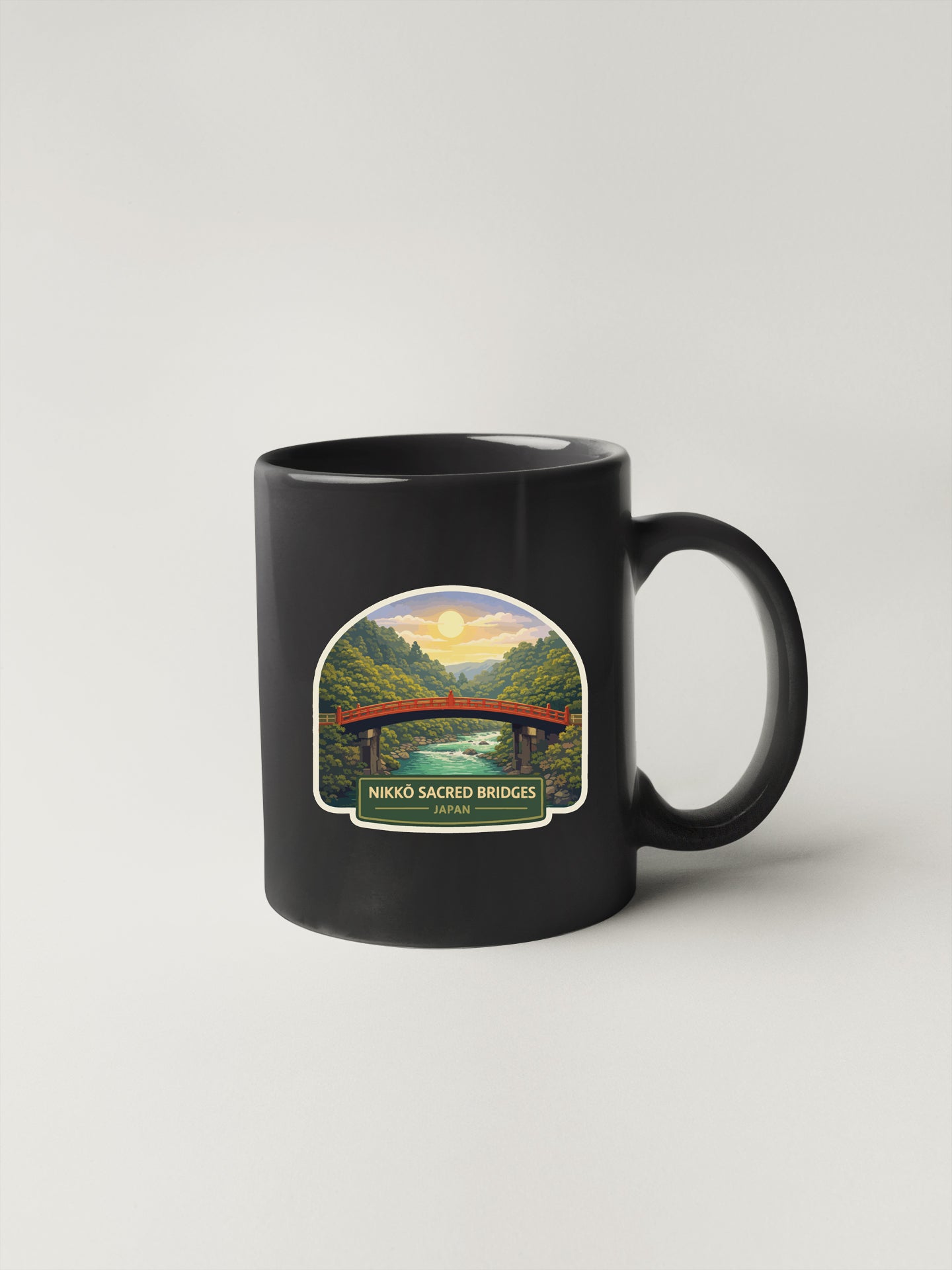 A black coffee mug with a sticker depicting a scenic landscape featuring a bridge and a sunset.