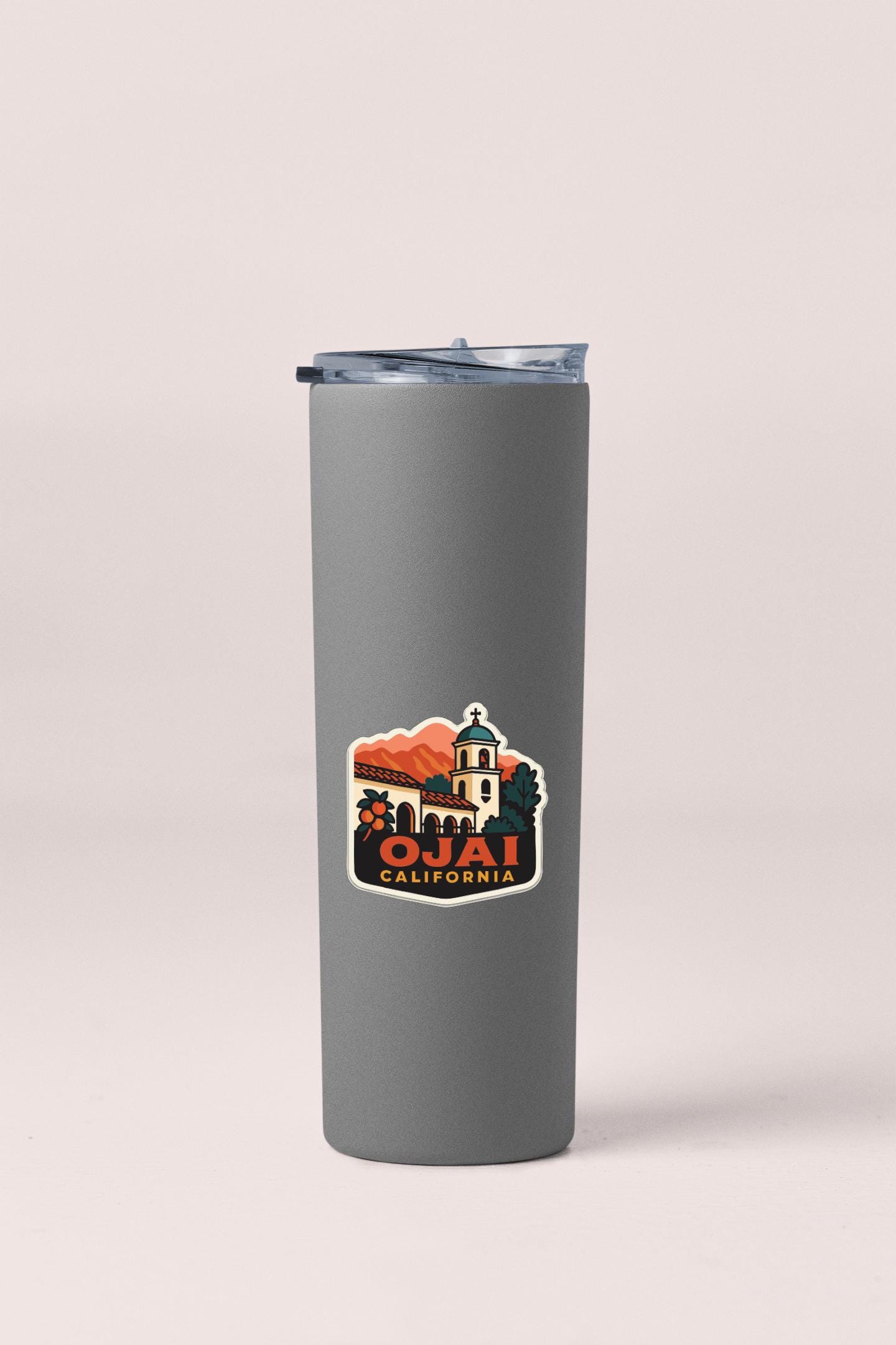 A gray insulated tumbler with a sticker depicting a scenic view of California.