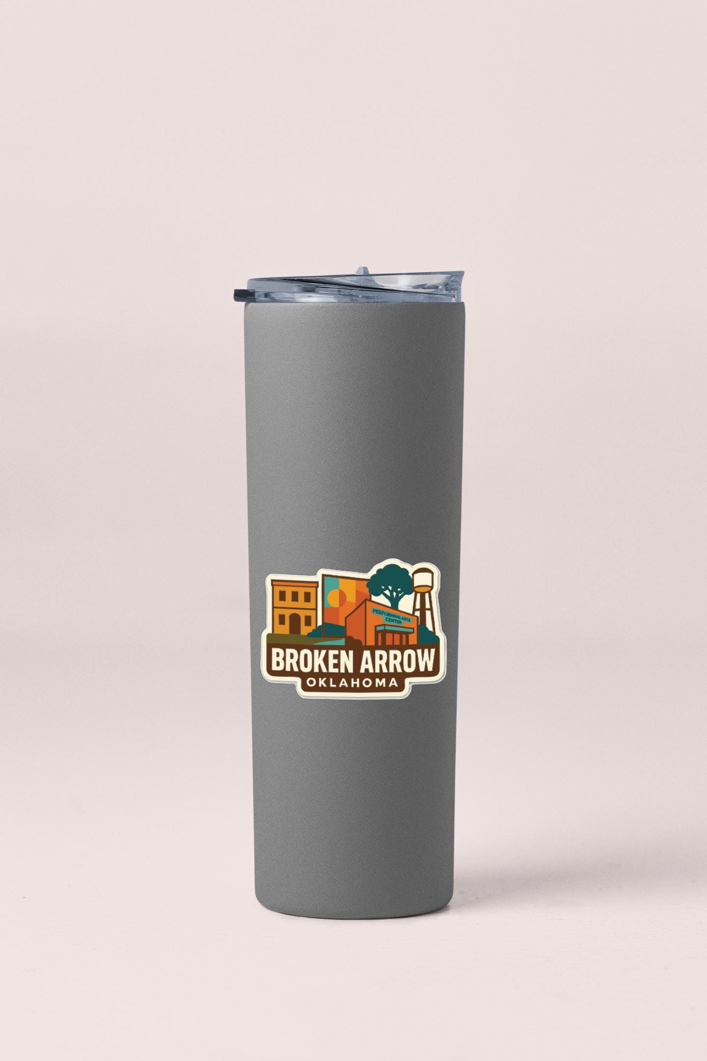 A gray insulated tumbler with a logo sticker on it, featuring an illustration of a cityscape with buildings and a water tower.
