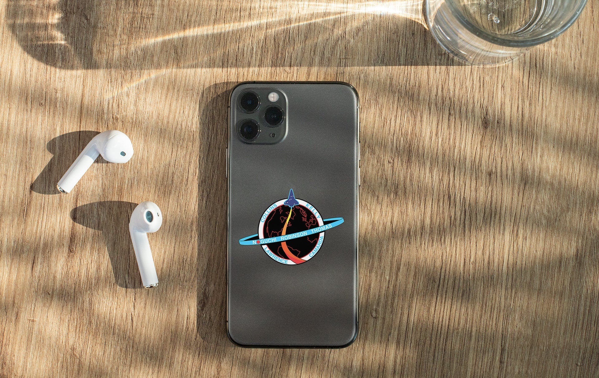 a cell phone with a sticker on it next to ear buds