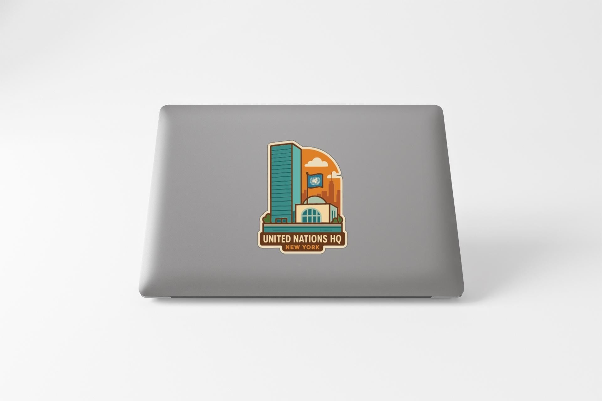 a sticker on the back of a laptop that displays a stylized illustration of a building, along with the text "UNITED NATIONS HQ" and "UNITED NATIONS".