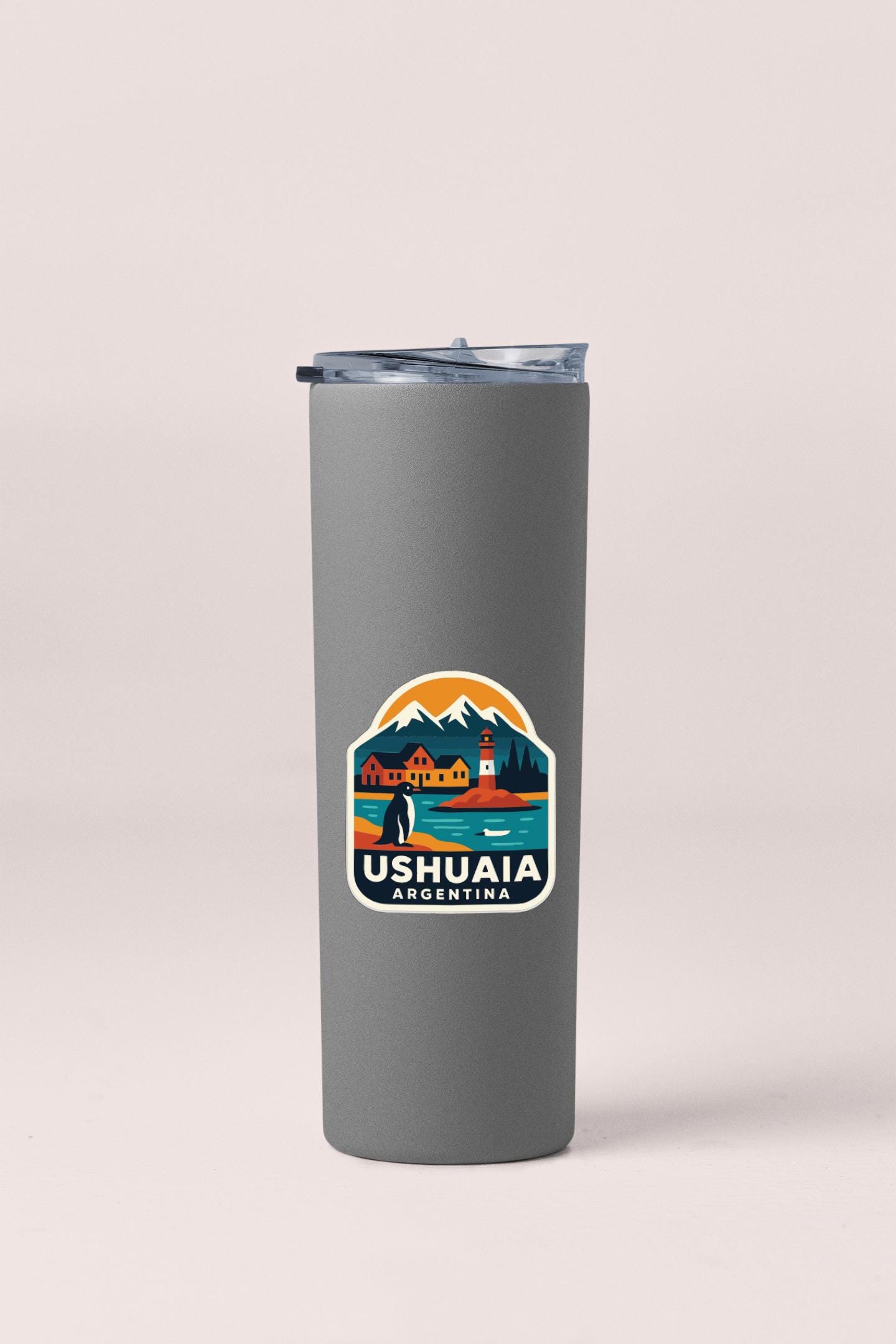 A gray insulated tumbler with a travel-themed sticker on it.