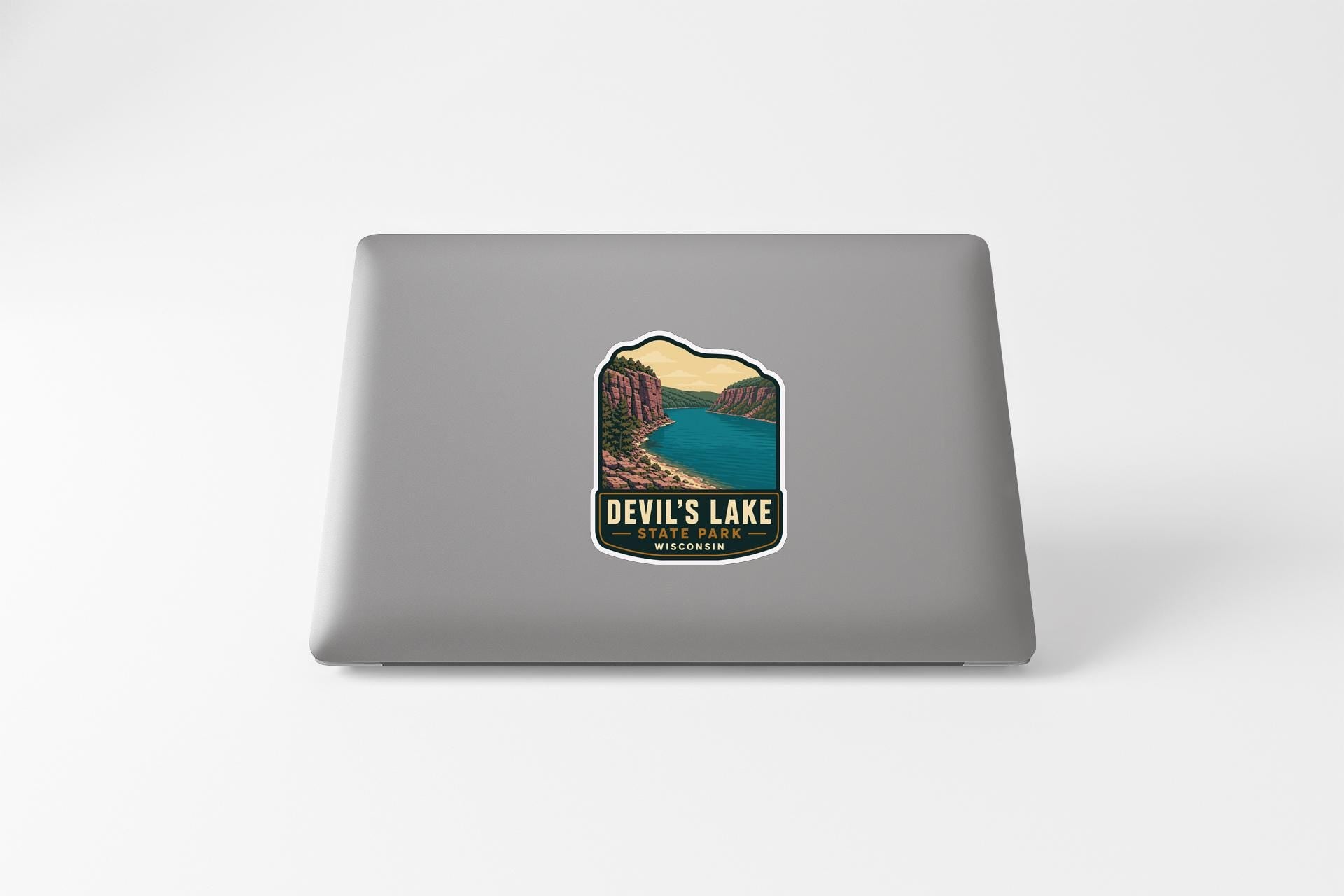 A sticker on the back of a laptop, depicting a scenic landscape with a lake and mountains.
